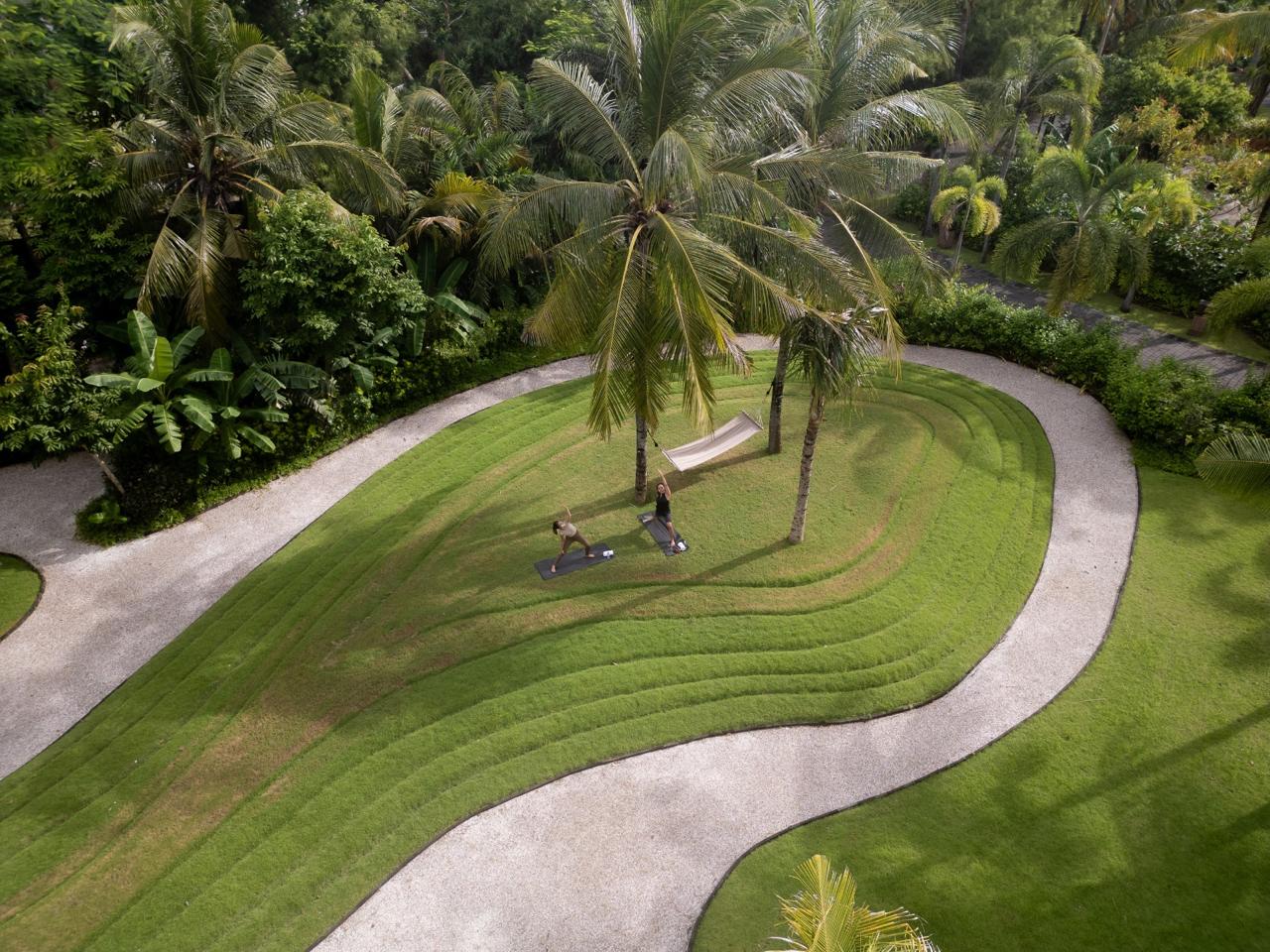 Hiker walking along a narrow mountain ridge at sunrise, surrounded by misty rolling hills.