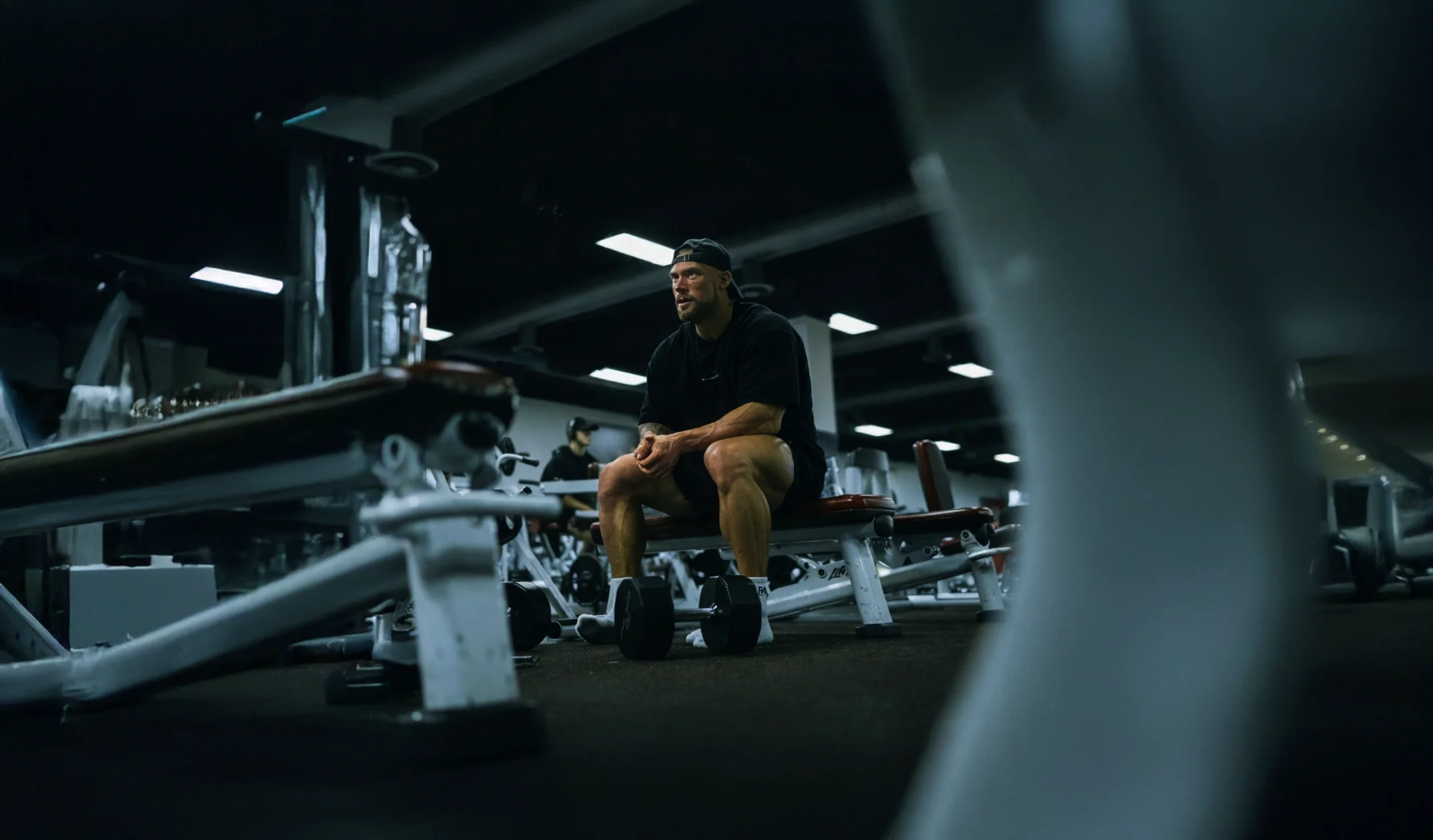 Bodybuilder on a gym bench, a dumbbell nearby.