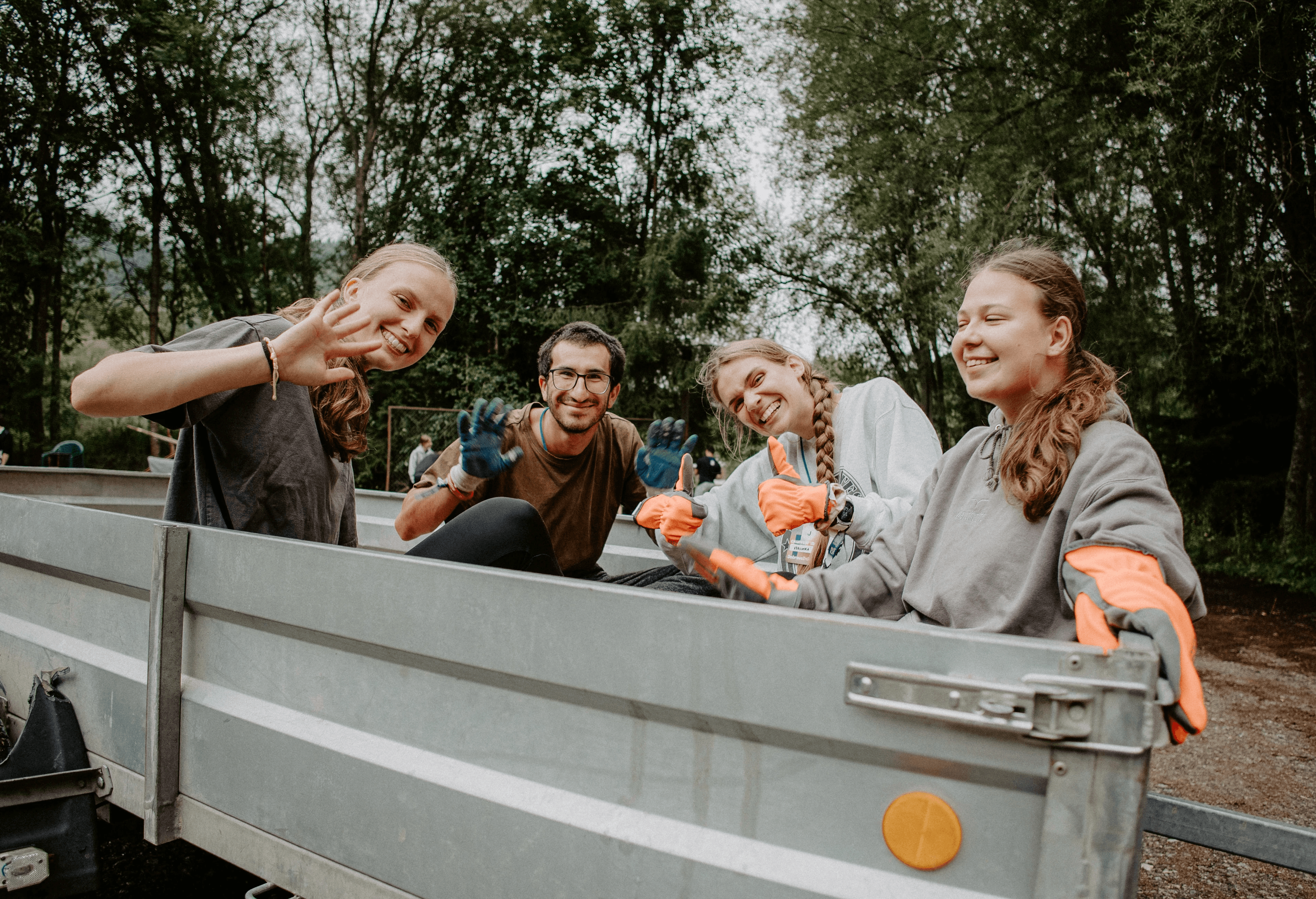 Four hands clinking beer glasses over table of food
