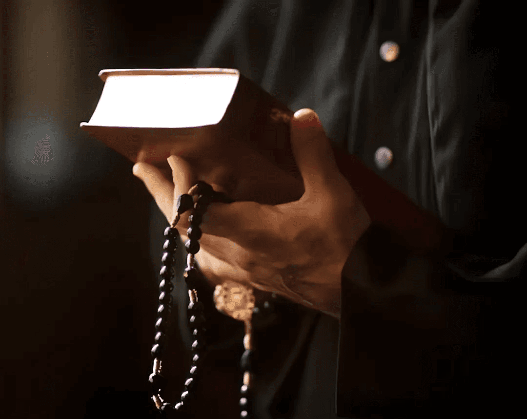 Hands holding prayer beads and a prayer book