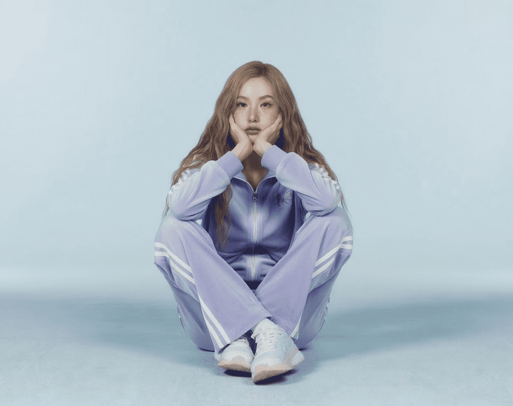 Woman in a purple tracksuit sitting on the floor against a blue background