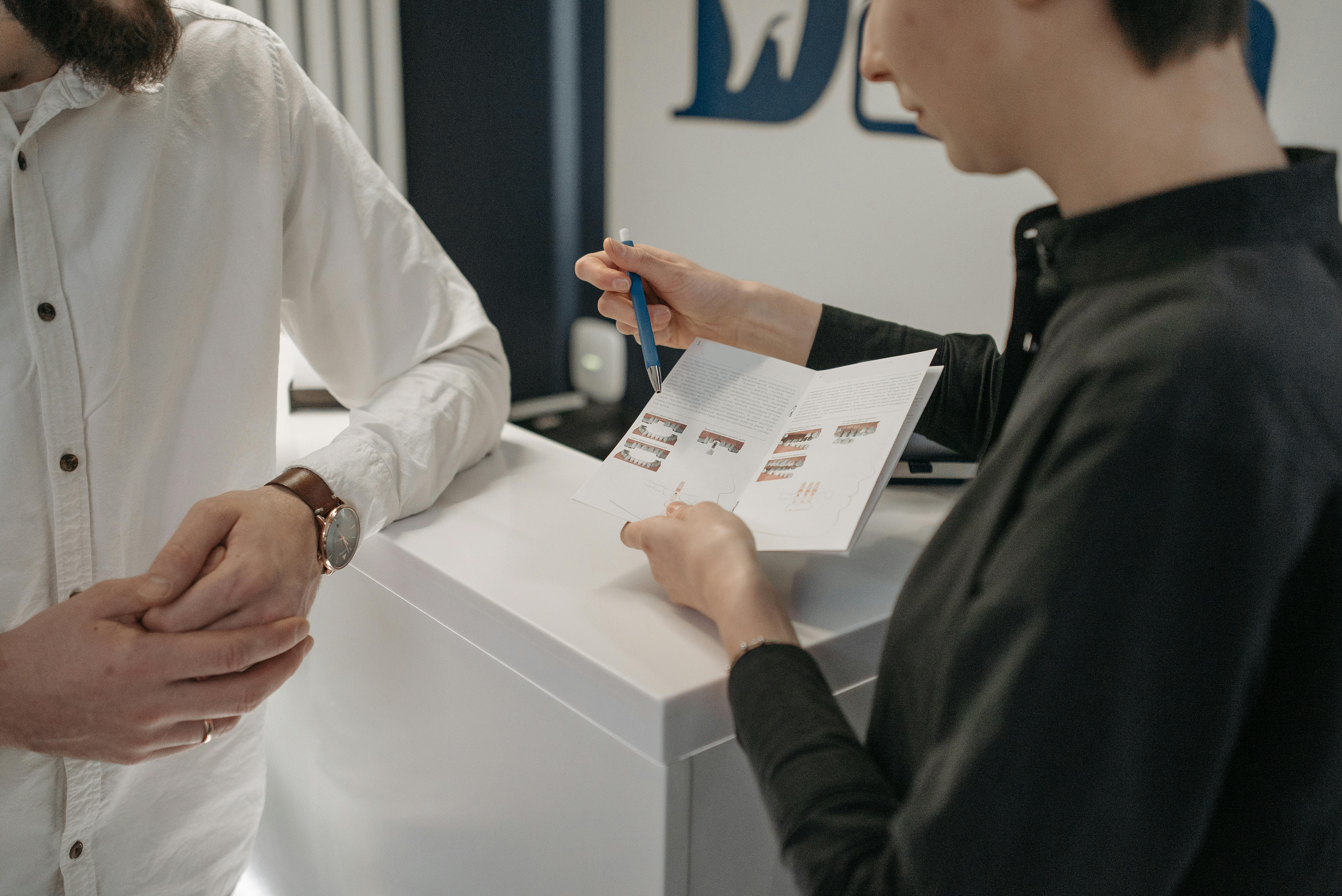 dental office manager showing pamphlet to customer