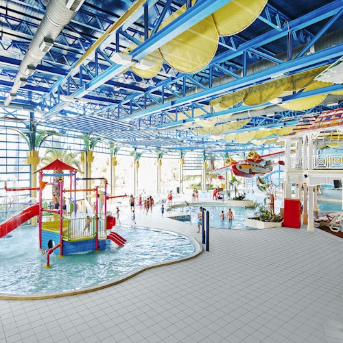 Indoor waterpark with a splash zone, waterslides, a lazy river, and people enjoying various attractions under a high, blue ceiling.