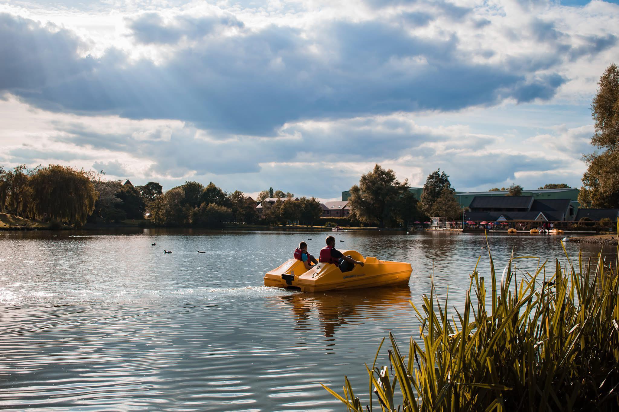 A yellow pedalo with two people cross a lake