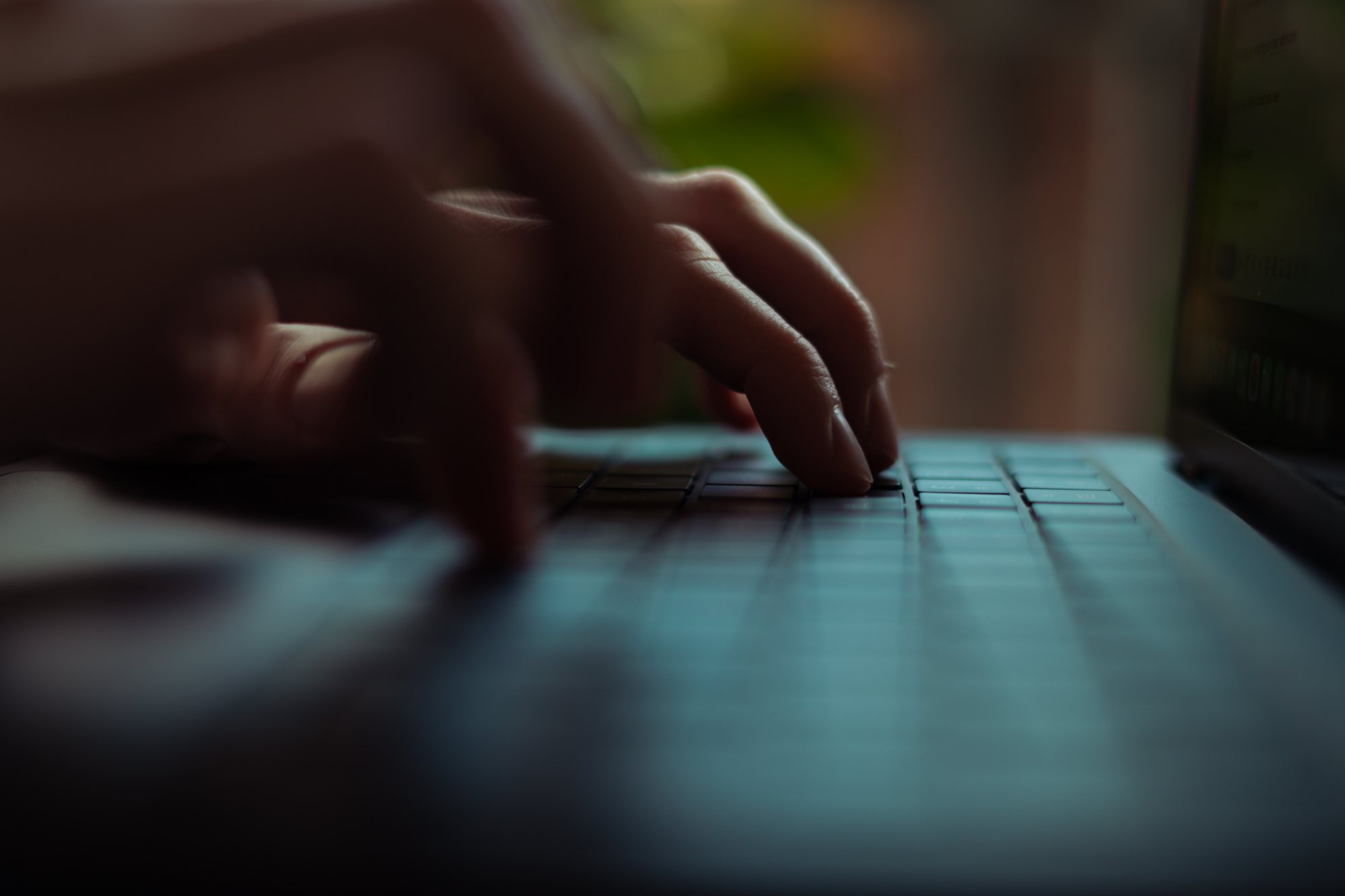 Hands typing on a laptop in low light