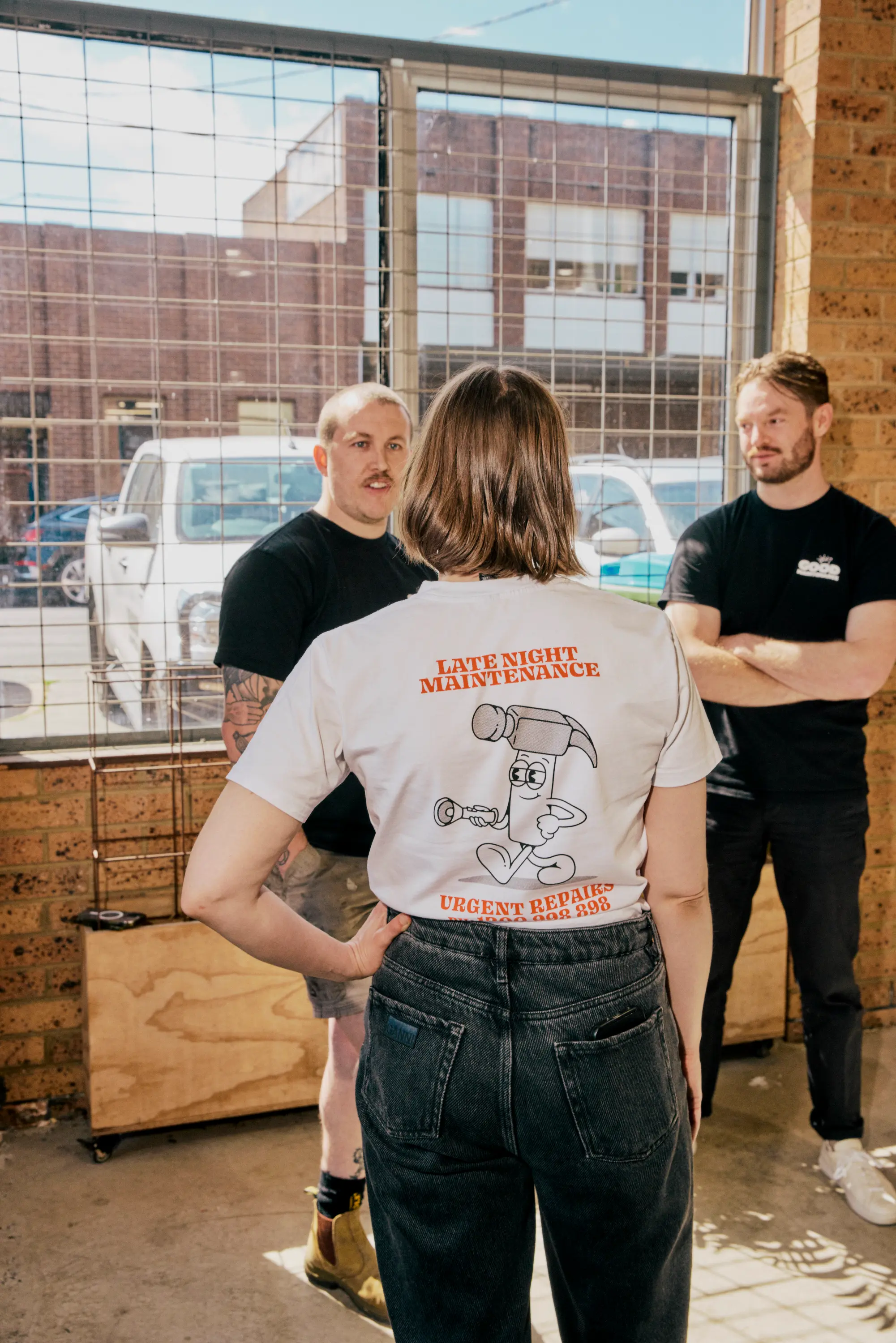 Team Member posing with back to camera displaying graphics on her Good Maintenance shirt.