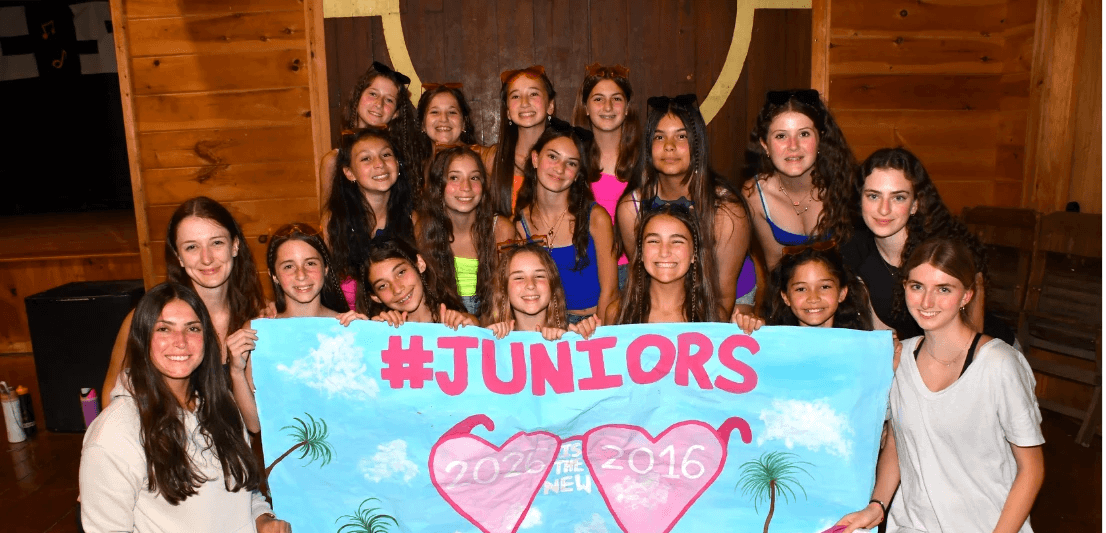 Group of campers holding a #Juniors banner at an evening event