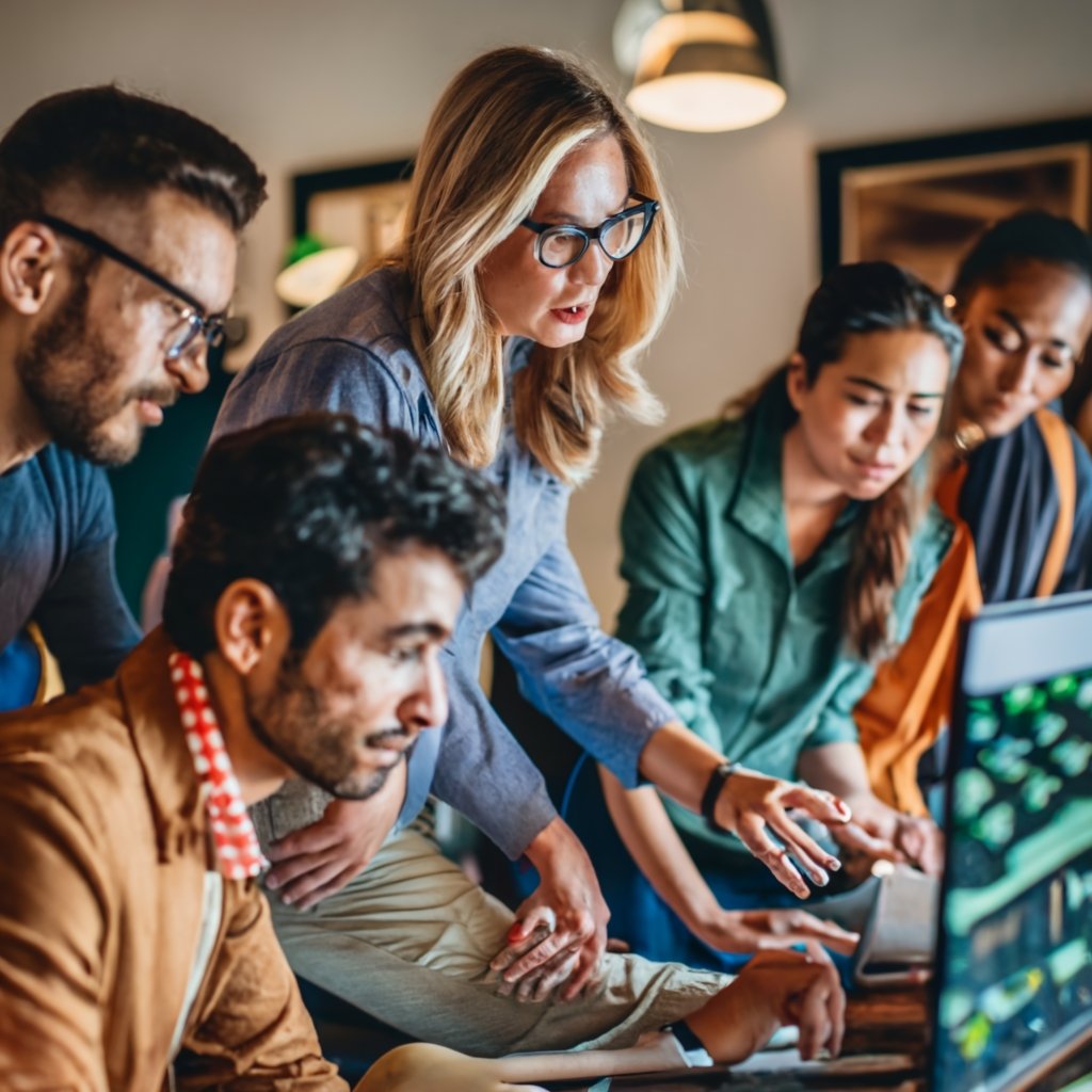 A group of diverse individuals gathered around a computer screen, visibly engaged as they navigate the My USCIS portal.