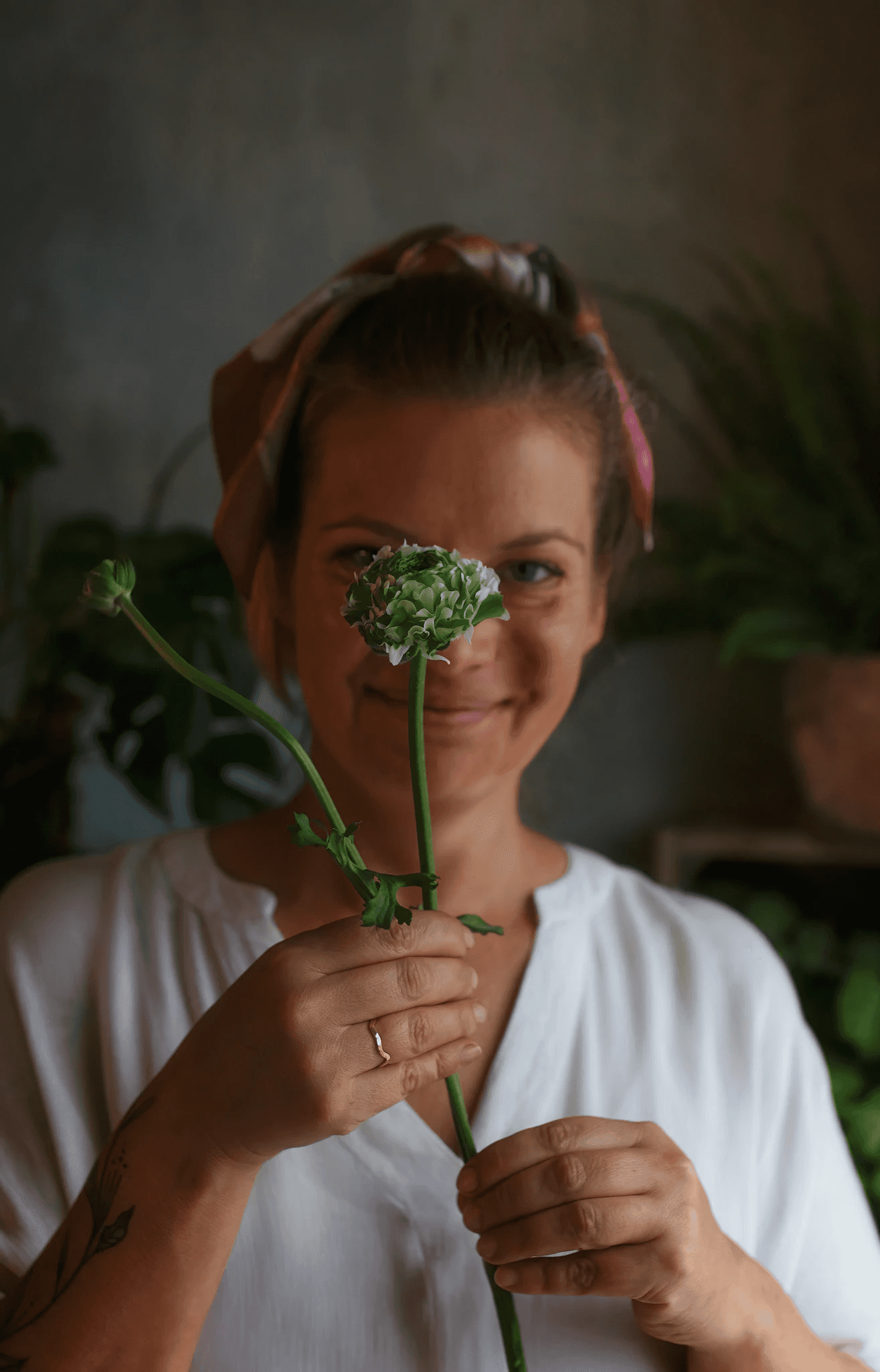 A portrait of a woman holding a flower in front of the camera