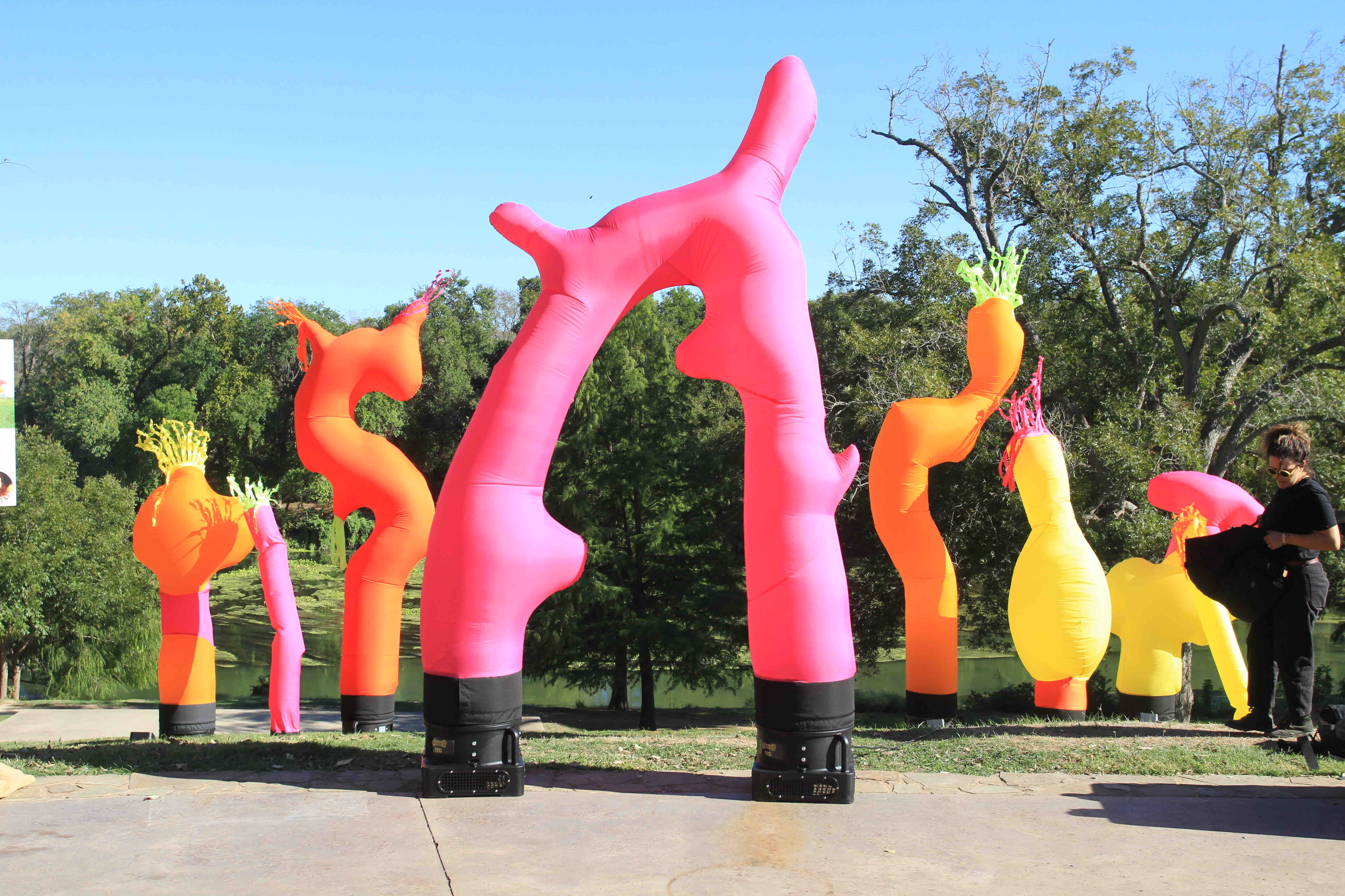 Colorful inflatable animals of various shapes and sizes standing outdoors against a clear blue sky.