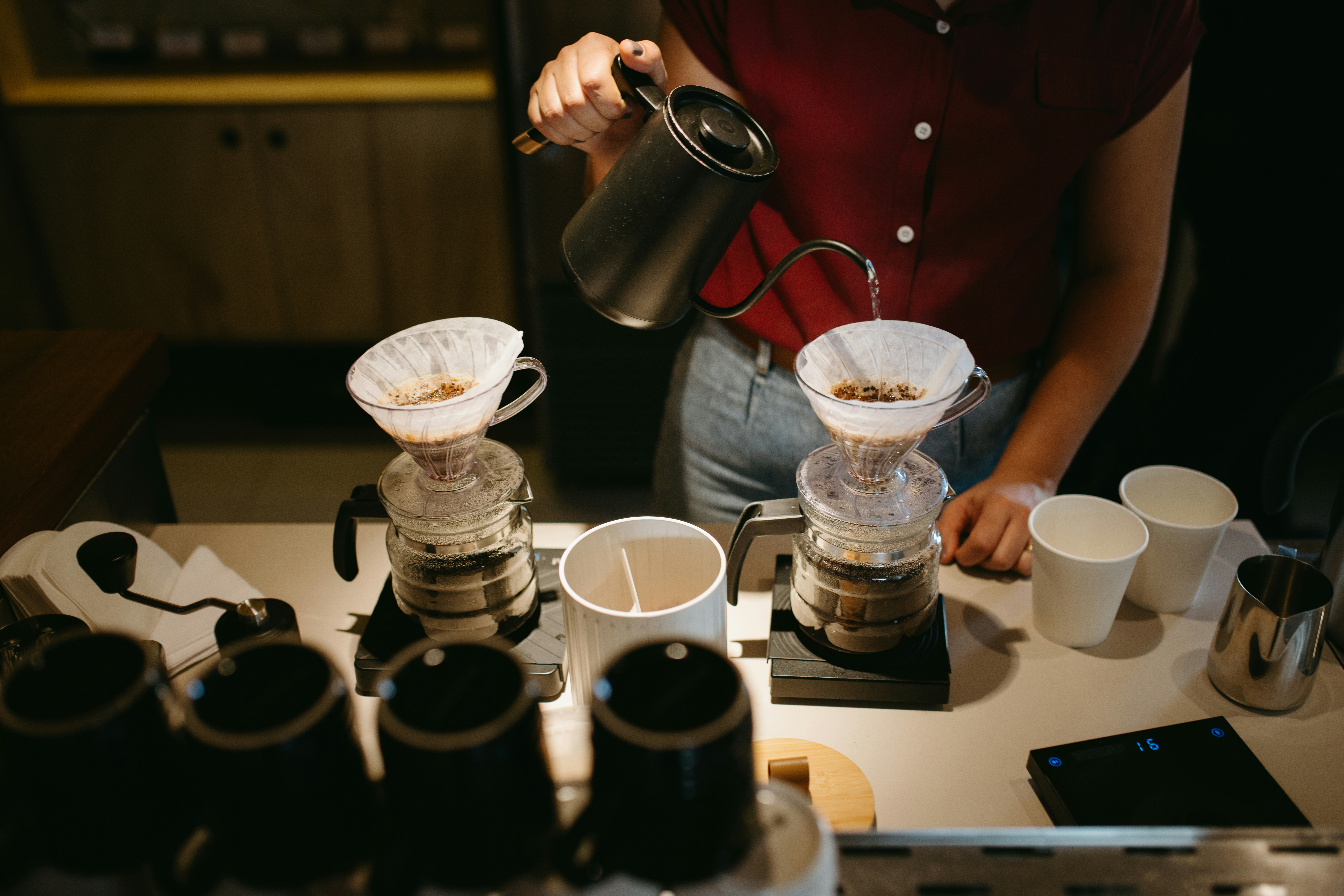 A woman pours coffee from a coffee maker