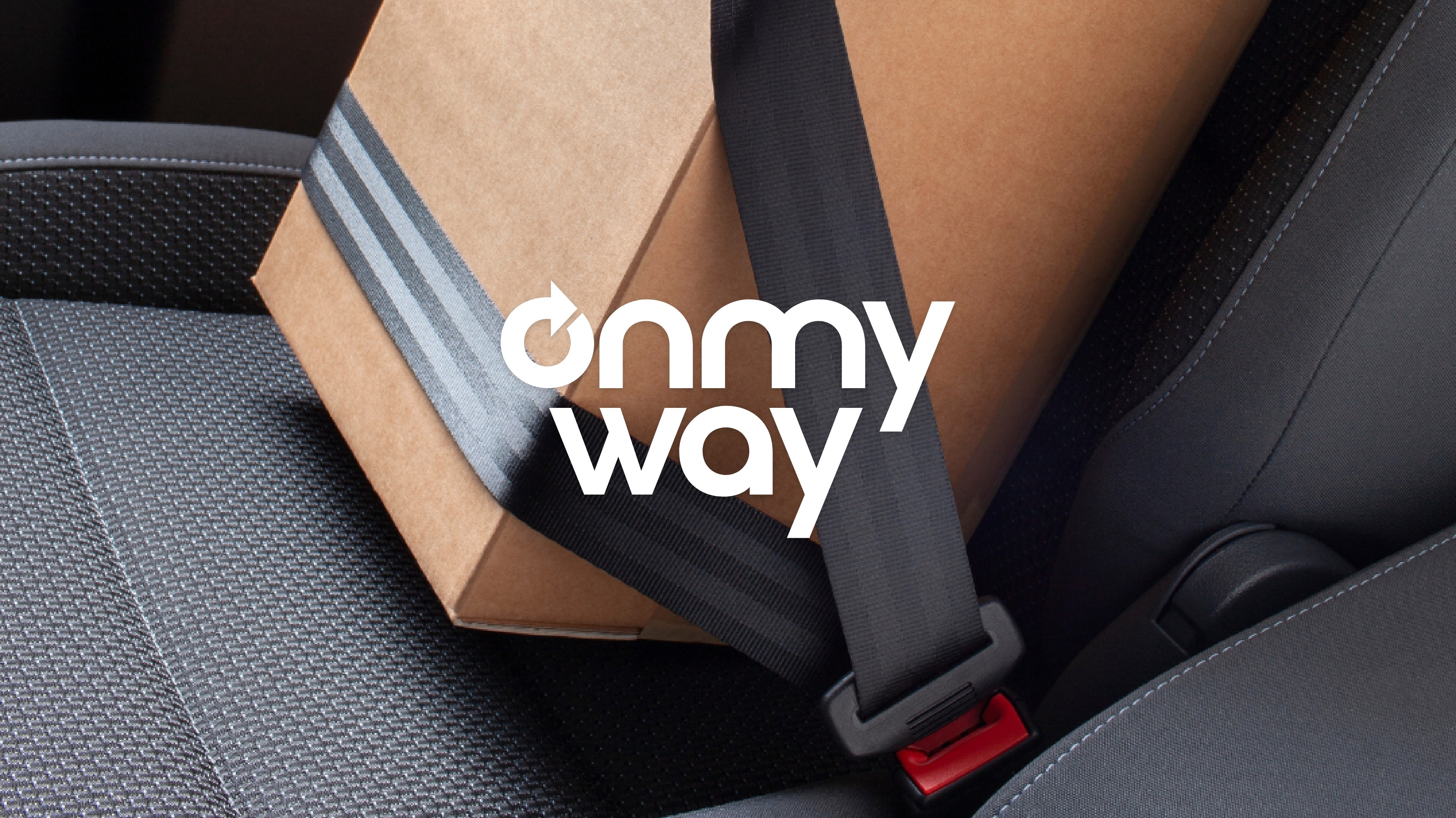 OnMyWay logo over a photo of a cardboard package seat buckled into a seat of a car