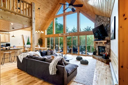 Bright cabin great room with vaulted windows and a stone fireplace
