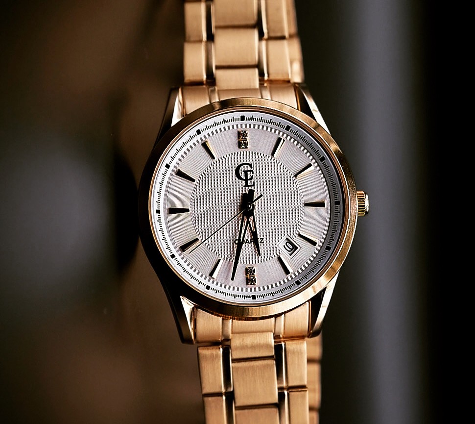 A white face watch with a gold band.