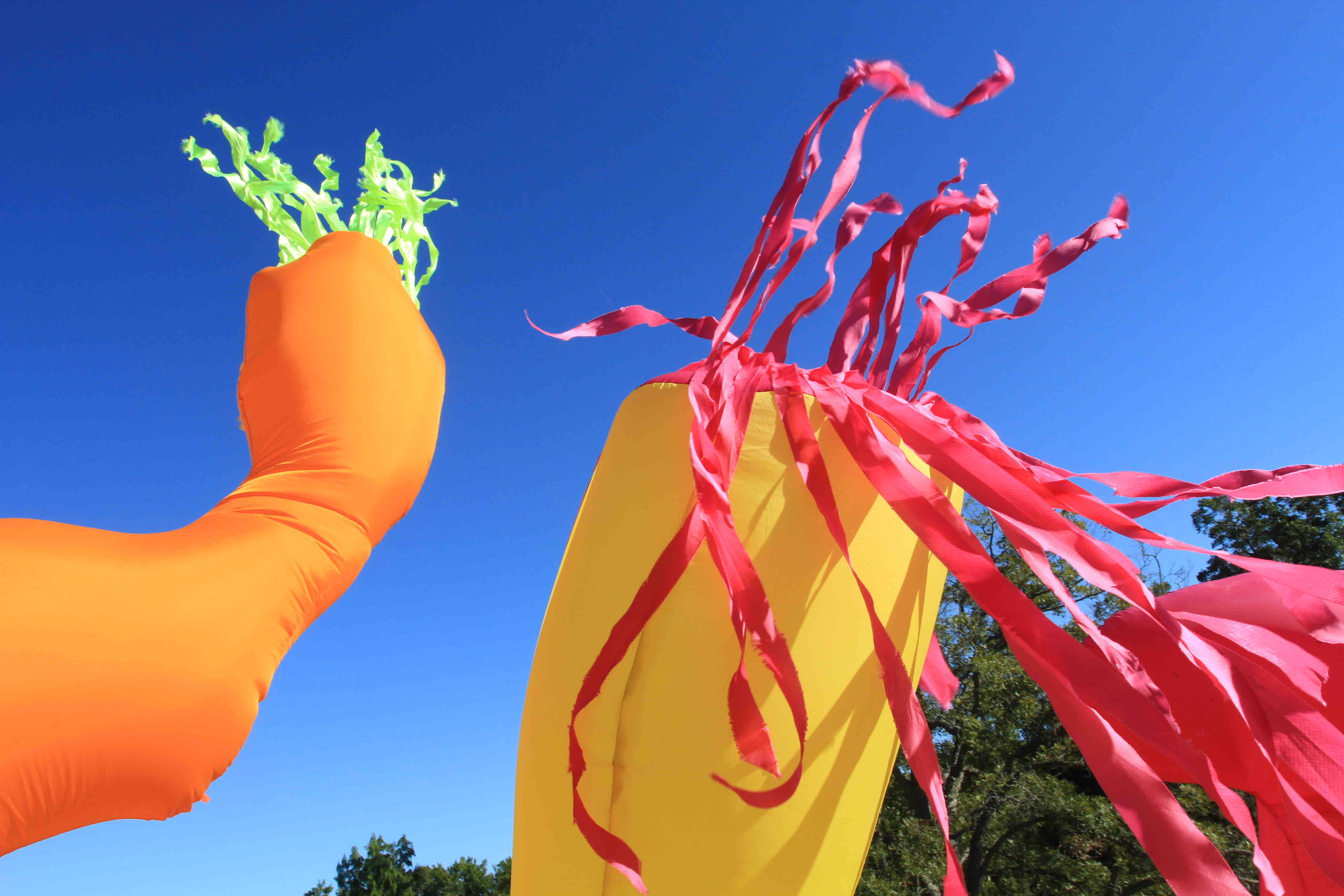 Colorful inflatable decorations with a bright blue sky background. One is orange with green accents, the other yellow with pink.