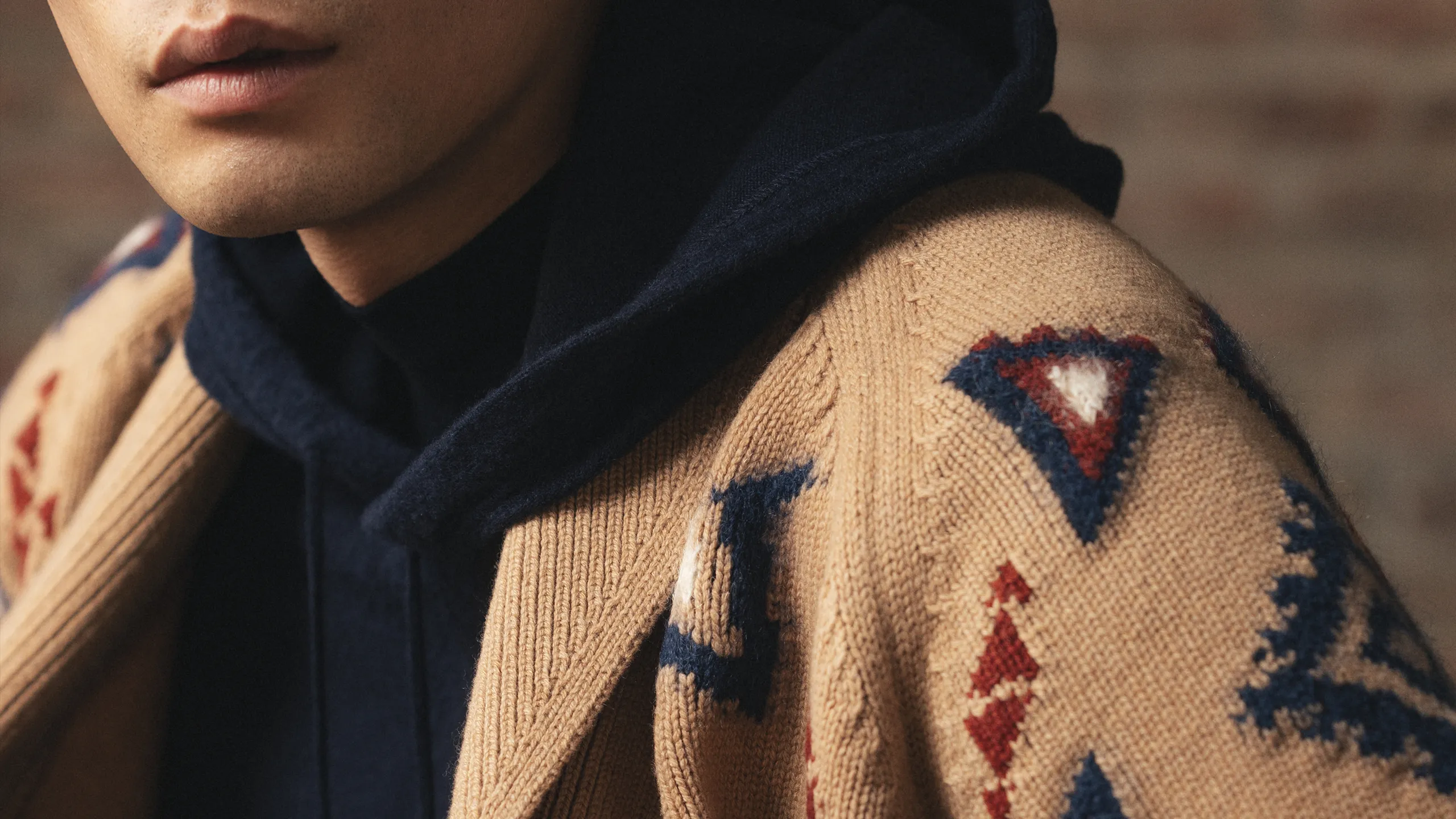 Close-up of camel cashmere cardigan with geometric jacquard motifs and navy hoodie – Annapurna