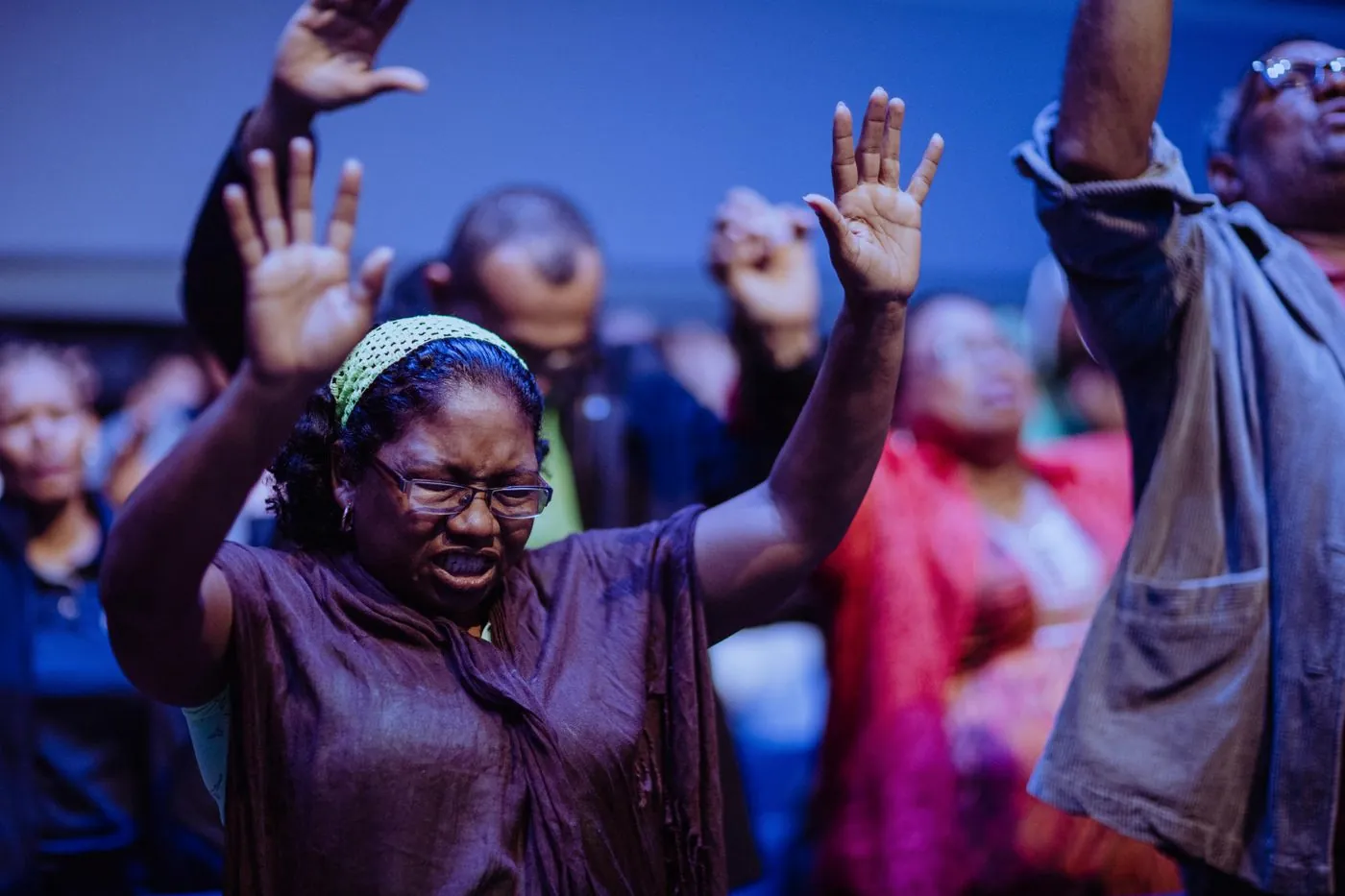 A woman smiling with both hands raised in worship