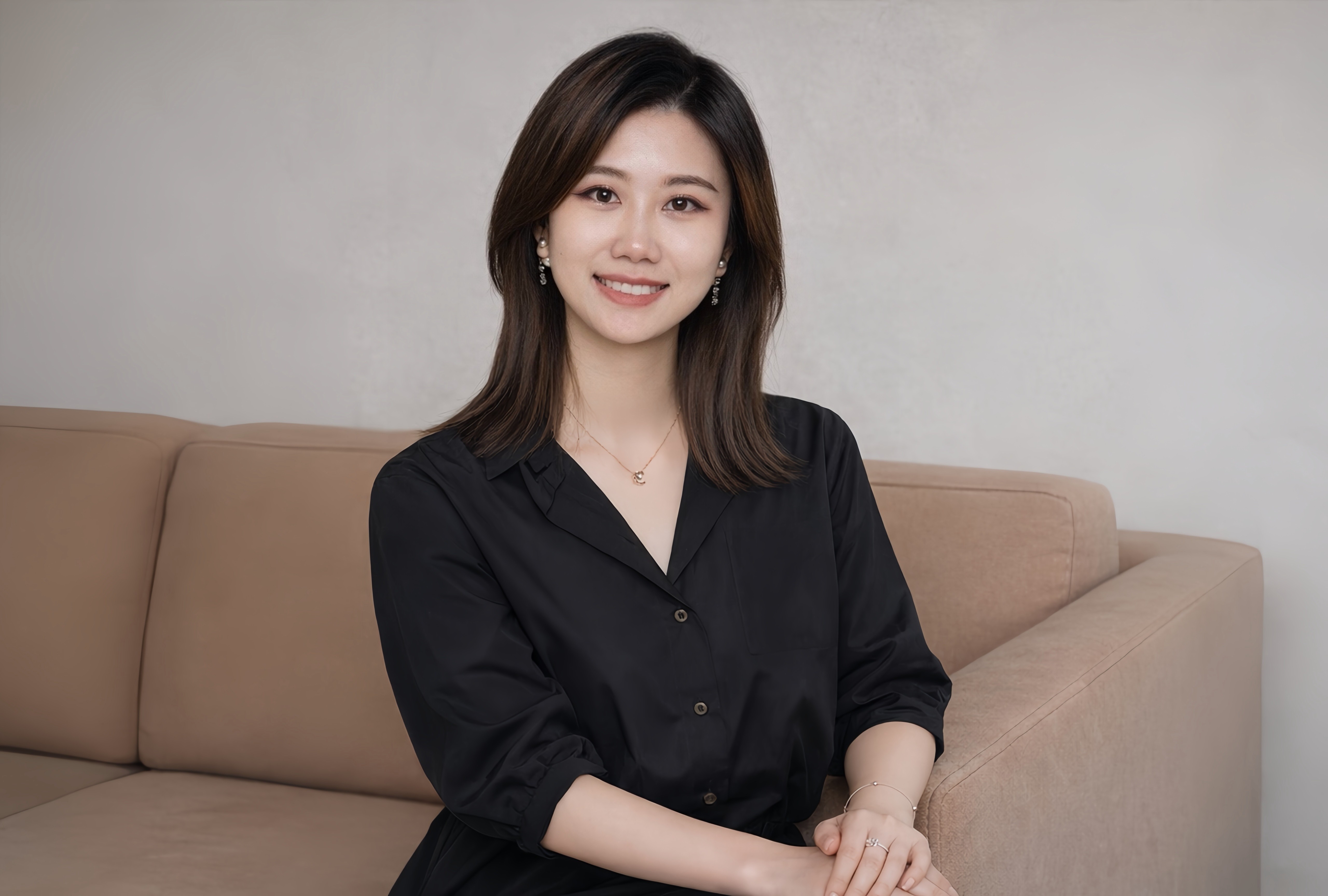Woman in a light suit sitting thoughtfully against a terracotta wall