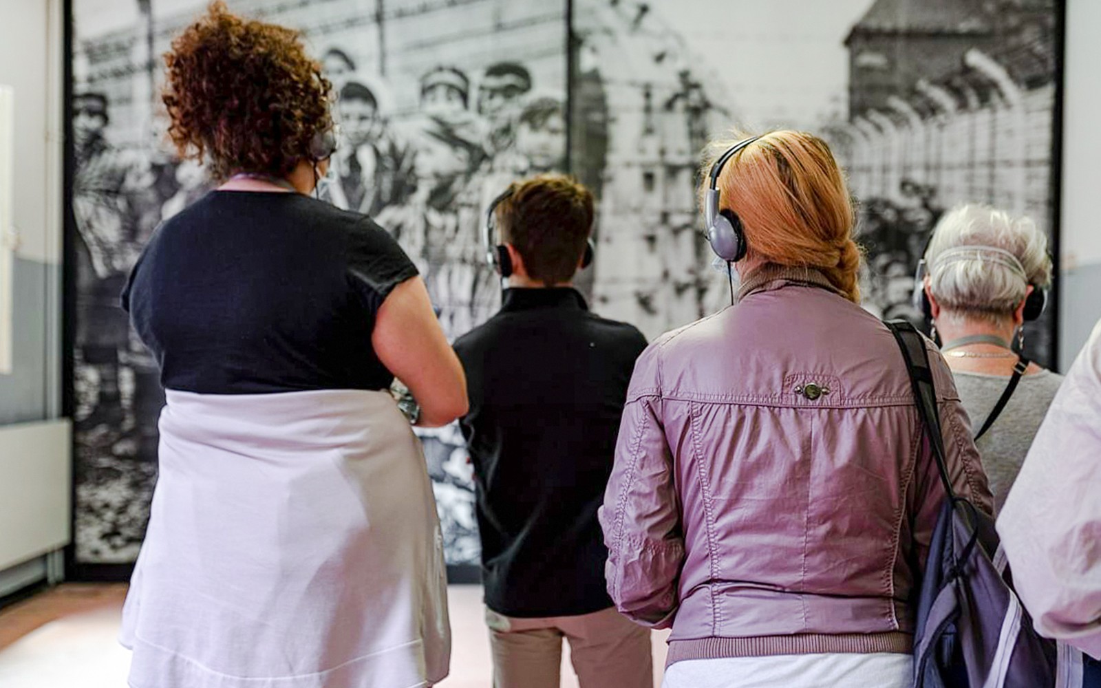 Besökare med hörlurar som tittar på utställningen vid Auschwitz Birkenau minnesmuseet.