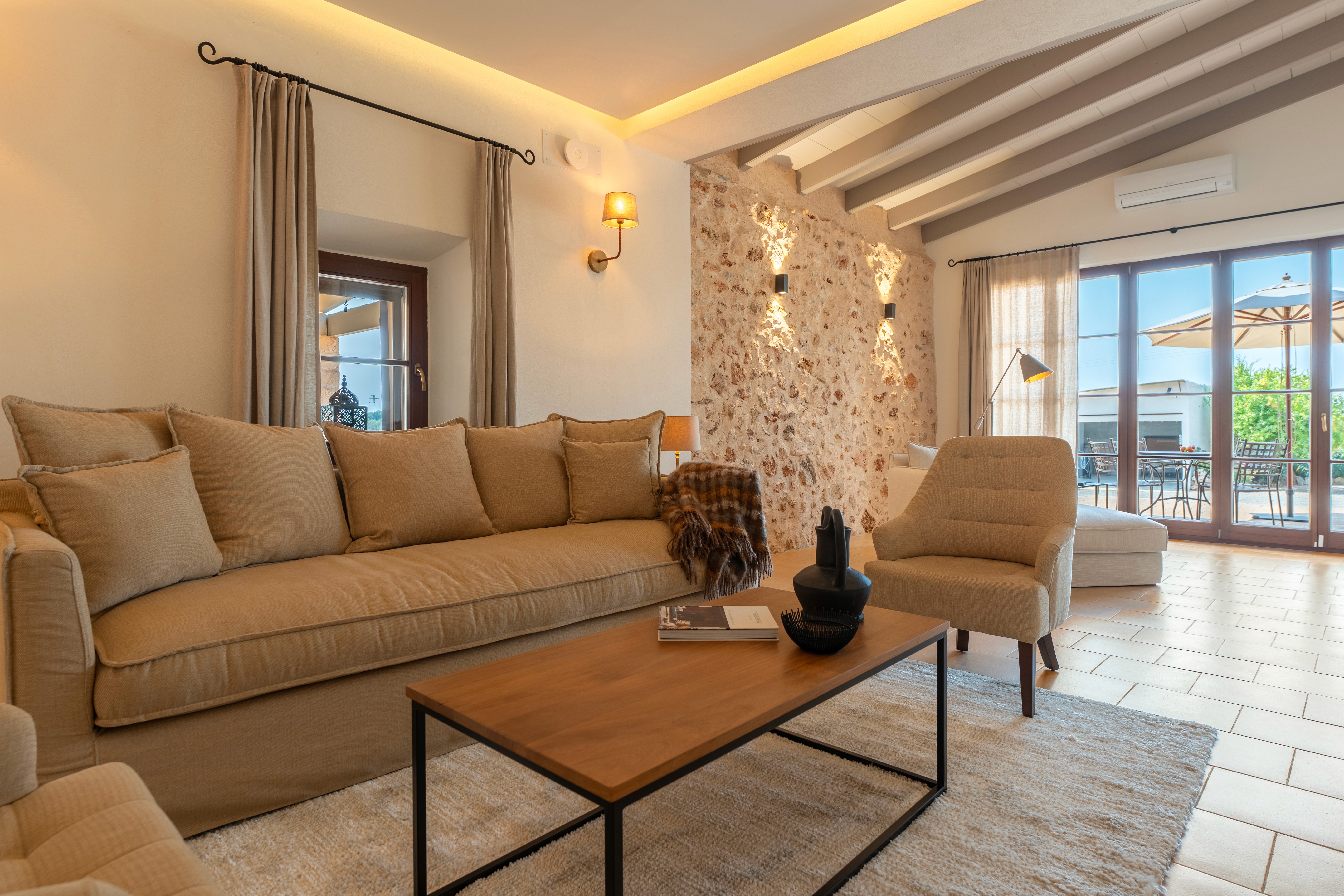 Wohnzimmer der Finca in Felanitx mit Holzbalkendecke, Leinensofa und ruhiger, traditioneller Gestaltung