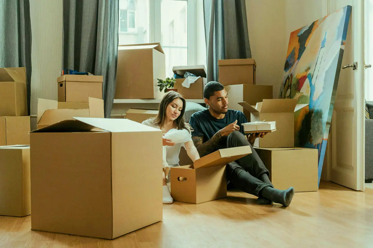 Couple sitted on the room floor organizing moving boxes.