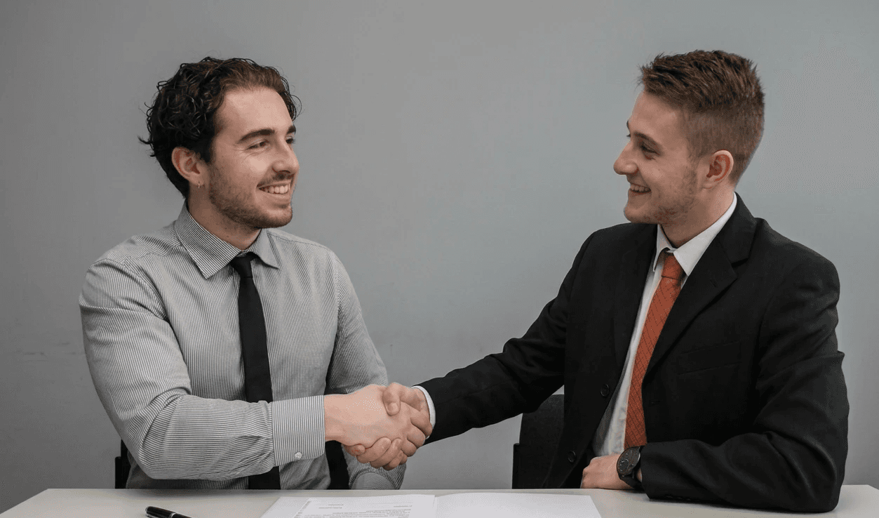 two men facing each other while shake hands and smiling