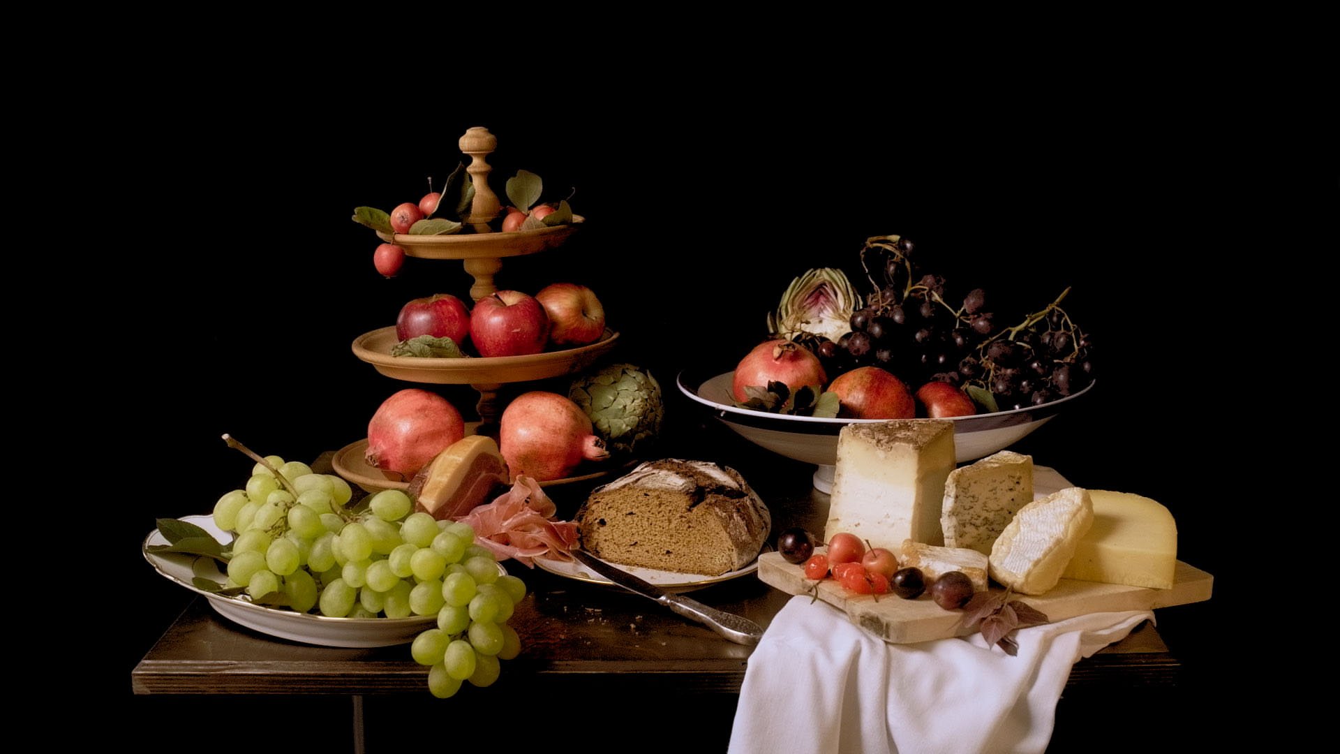 A decadent banquet of fruits, vegetables and cheese, presented in the style of a Dutch still life.
