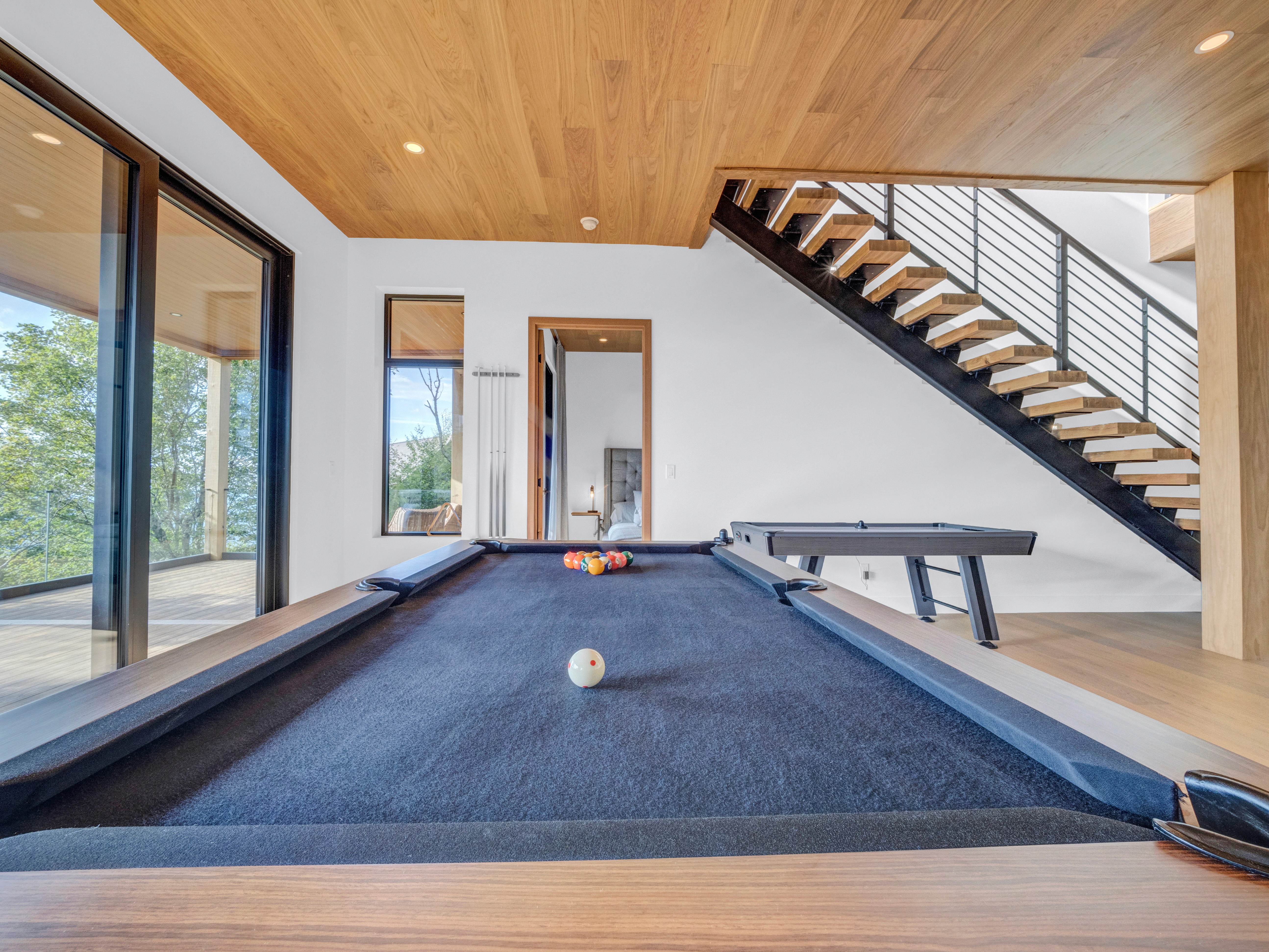 Close-up of a high-end wooden pool table with blue felt in a bright, contemporary cabin basement