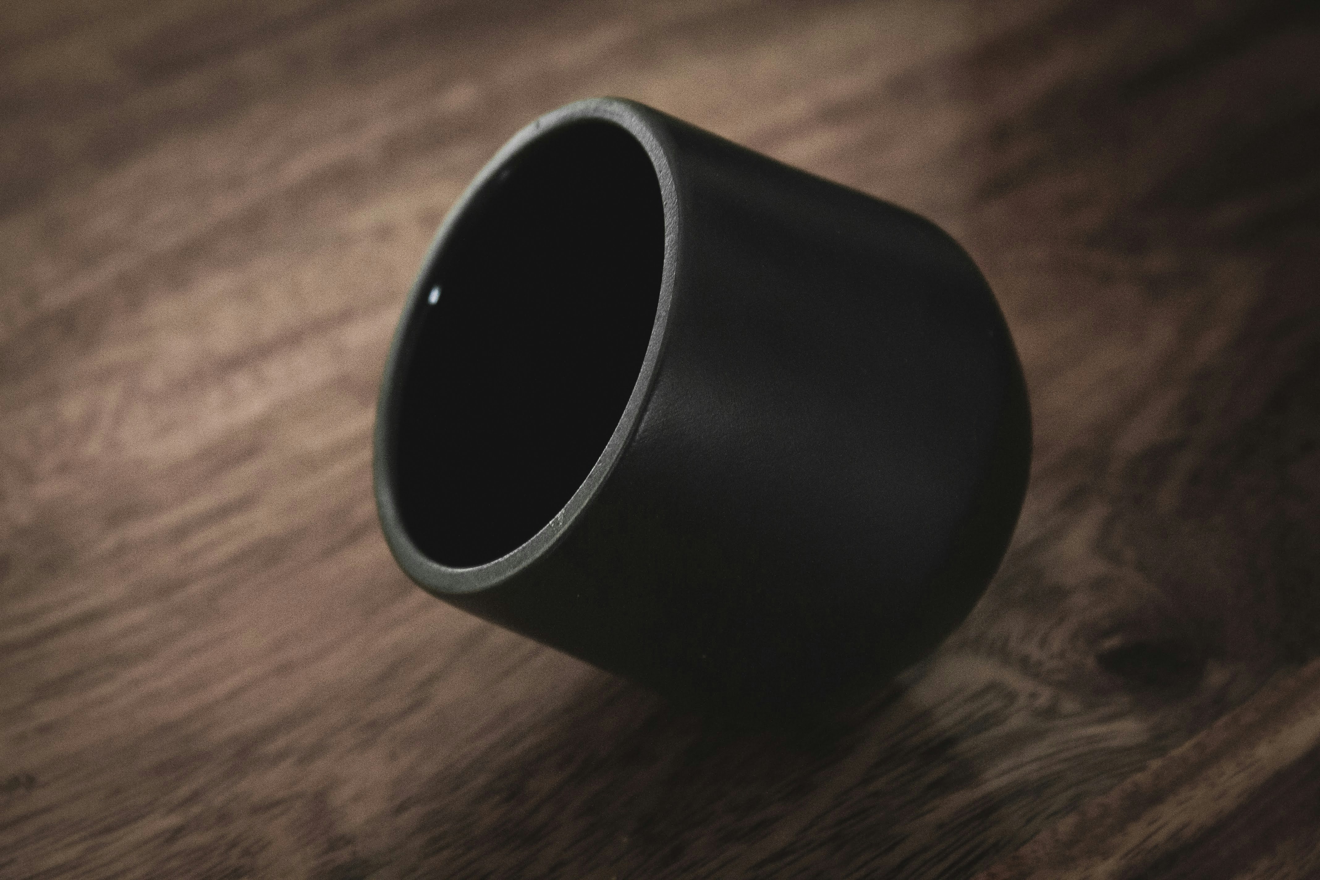 a black vase sitting on top of a wooden table