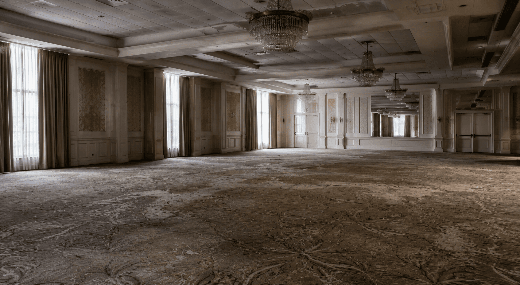 Worn ballroom carpet in an unfinished hotel event space.