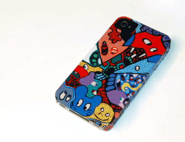The image shows a phone case with a colorful, cartoon-style design covering its front. The design features various abstract shapes and figures in a vibrant palette of red, blue, yellow, and green. The phone case is positioned at a slight angle on a white surface, revealing a clear or transparent back. It is unclear if the case is for a specific phone model or brand based on the image alone.