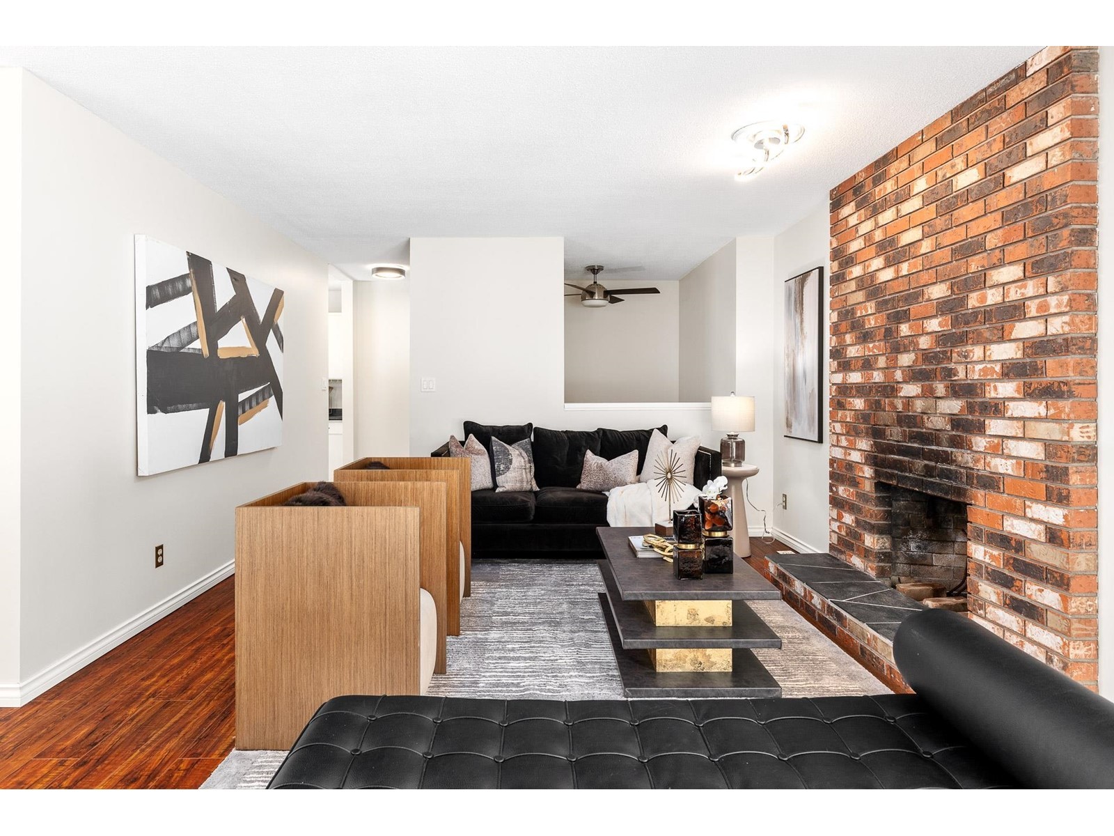 Modern living room with a stylish black sofa, wooden bar area, and a decorative brick wall in the background.