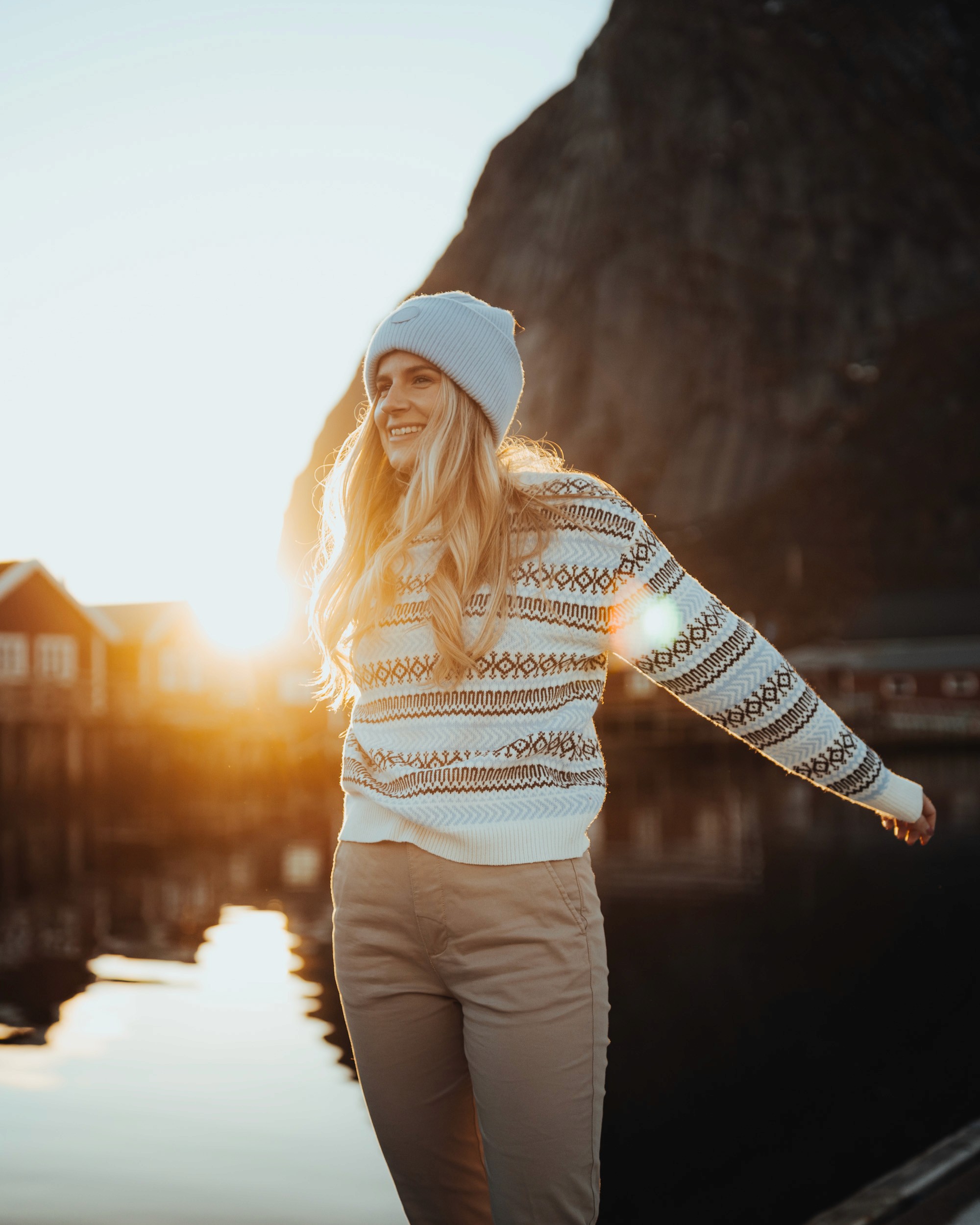Une fille en knowledge cotton apparel pose devant le soleil couchant, pull façon Fair Isle et bonnet sur la tête