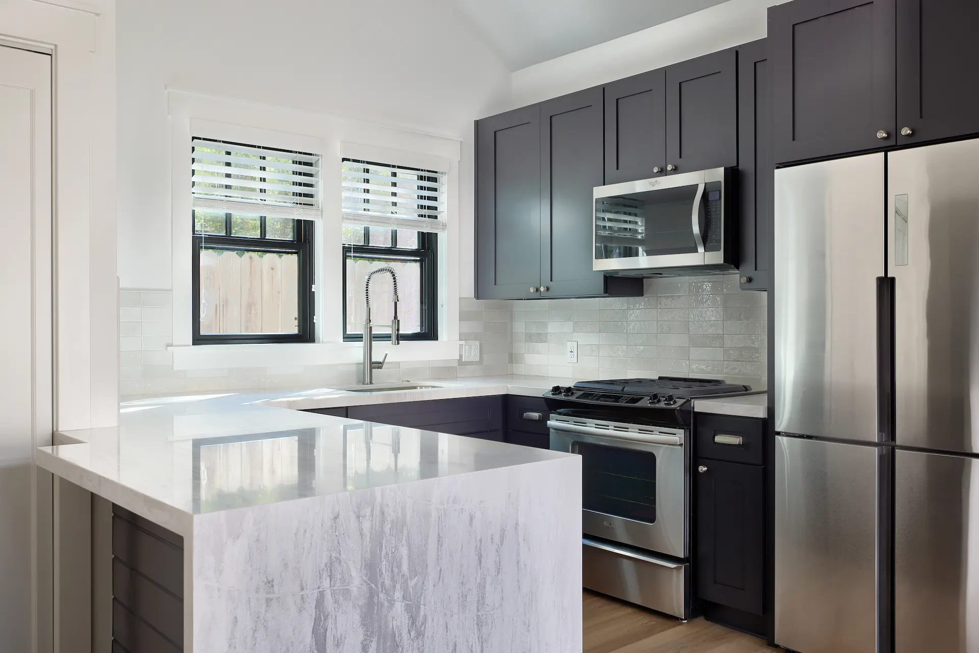 Full angled view of the kitchen in ADU Orange, where modern black cabinets and quartz countertops meet historical charm. Photo by Todd Huge.