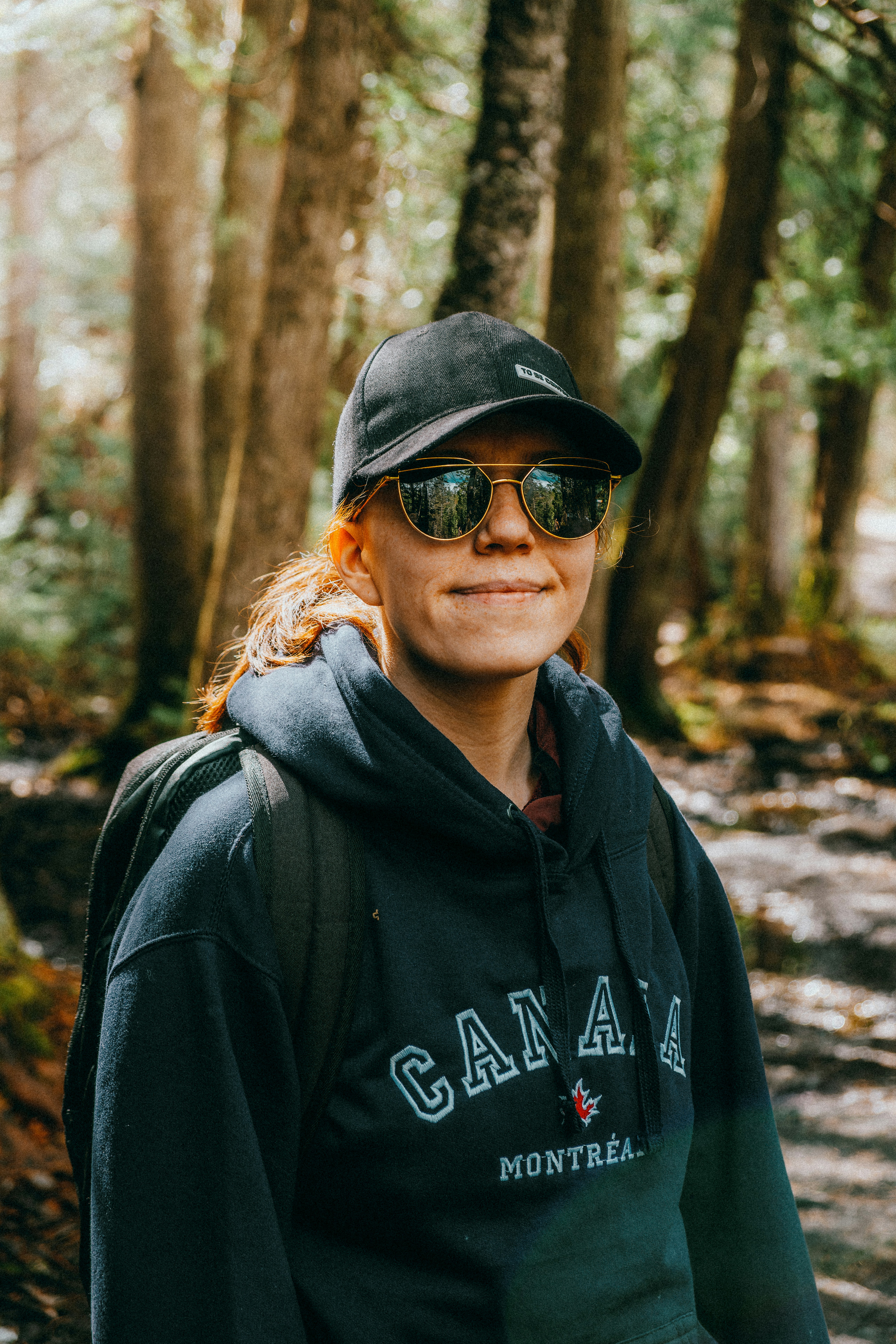 Woman wearing a canada hoodie and sunglasses in woods