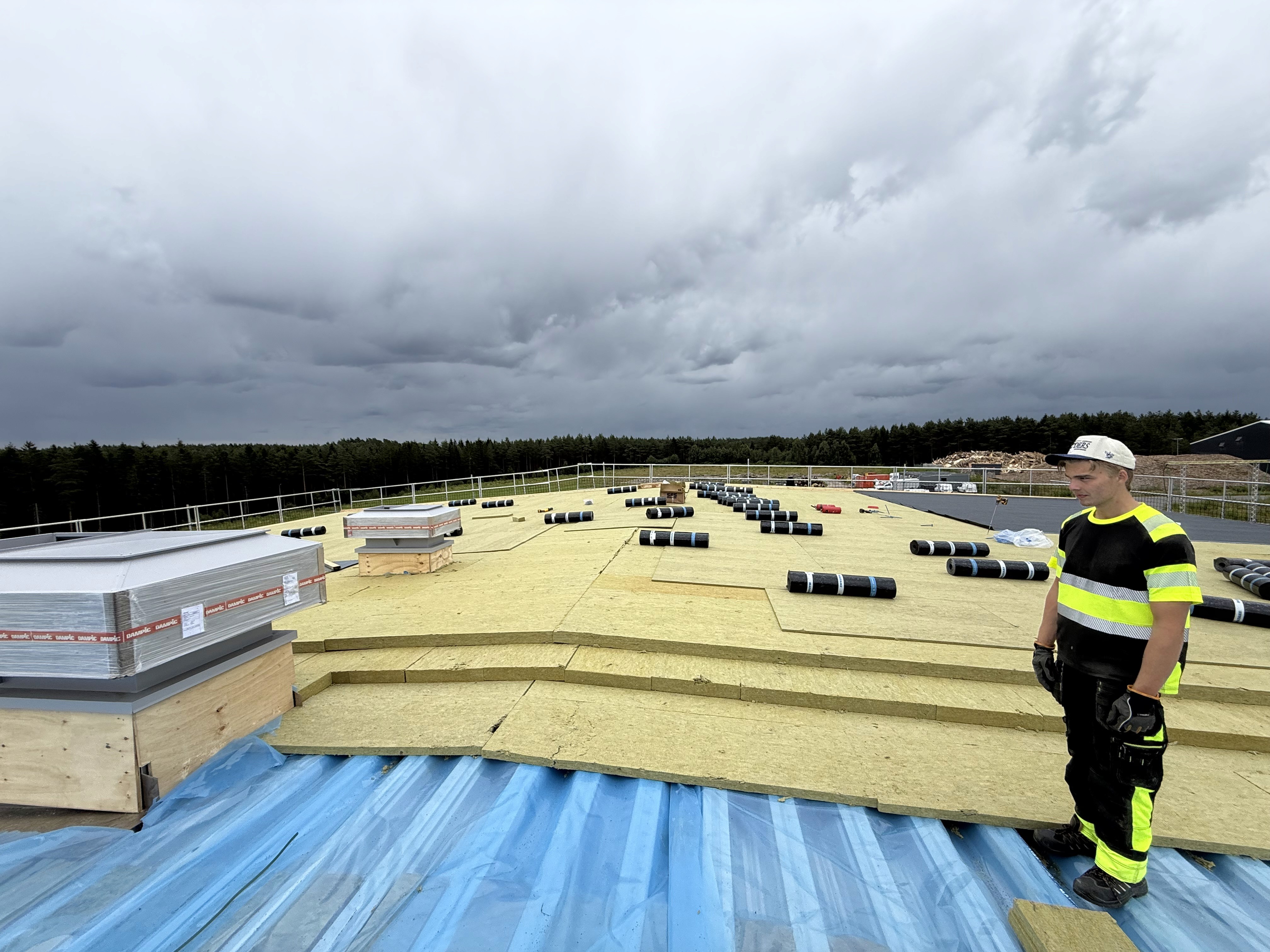 Roofer on the roof under dark storm clouds