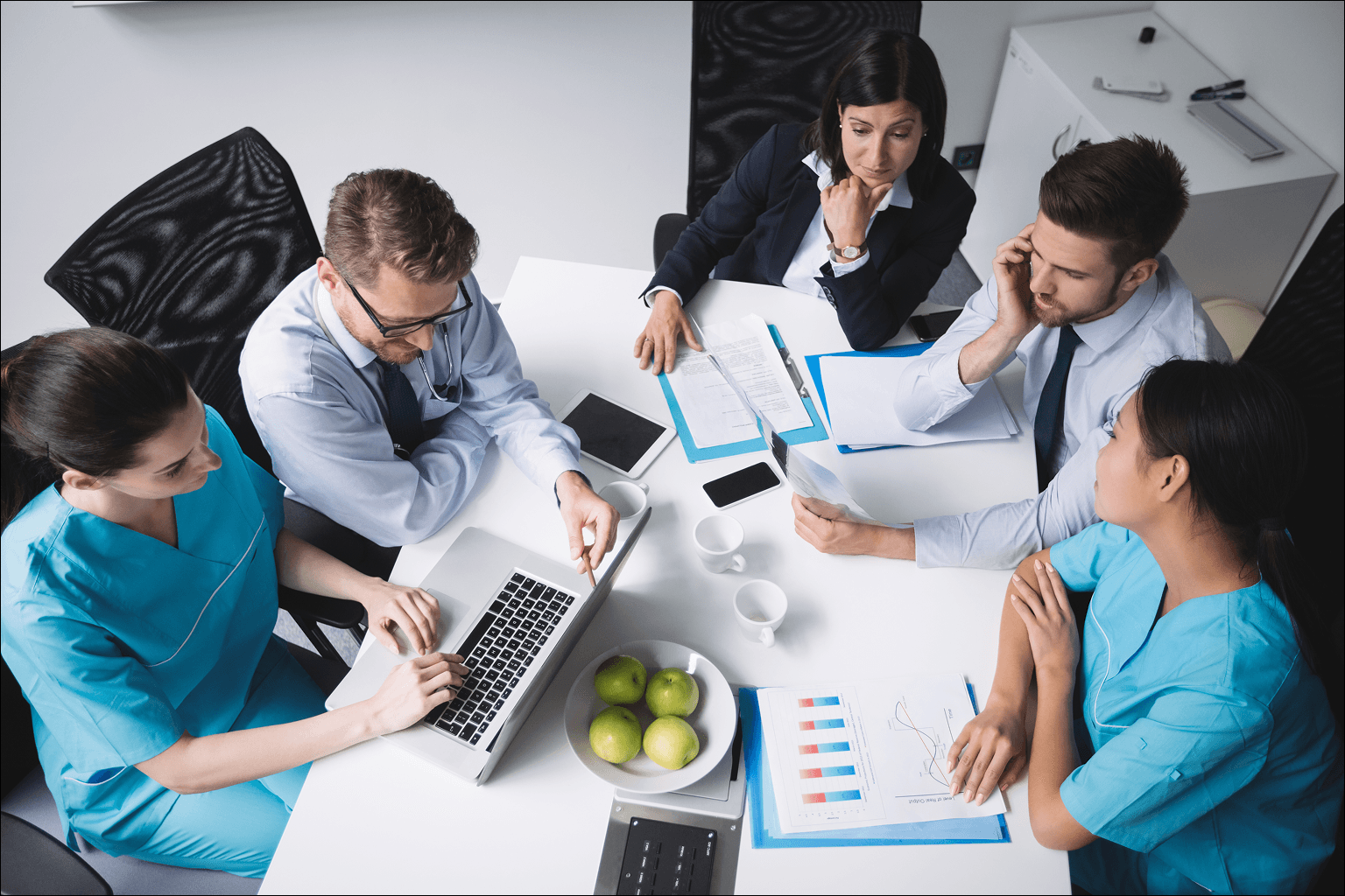 A healthcare and administrative team collaborating around digital reports and devices, illustrating coordinated omnichannel patient care.
