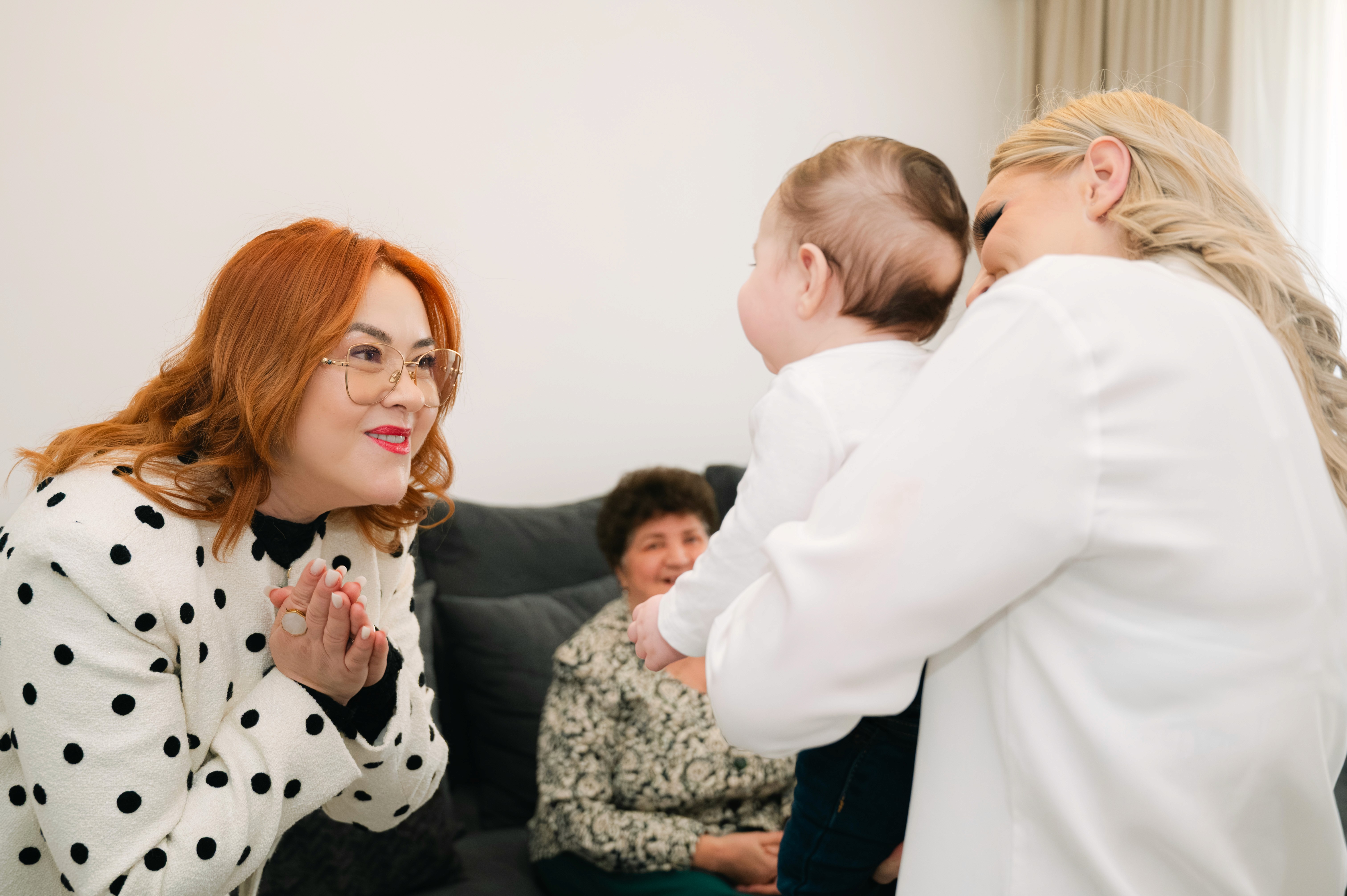 Nașa ținând copilul în brațe, moment emoționant surprins acasă.