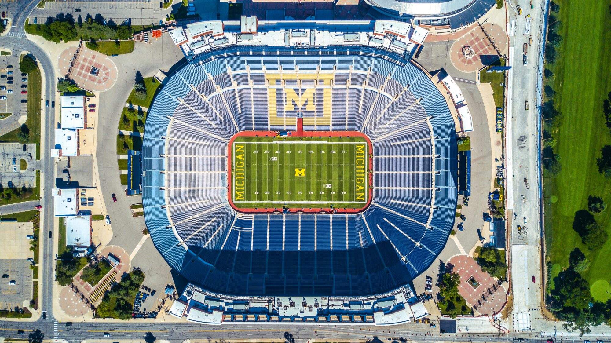 Aerial view of a large stadium with a green field and surrounding infrastructure.
