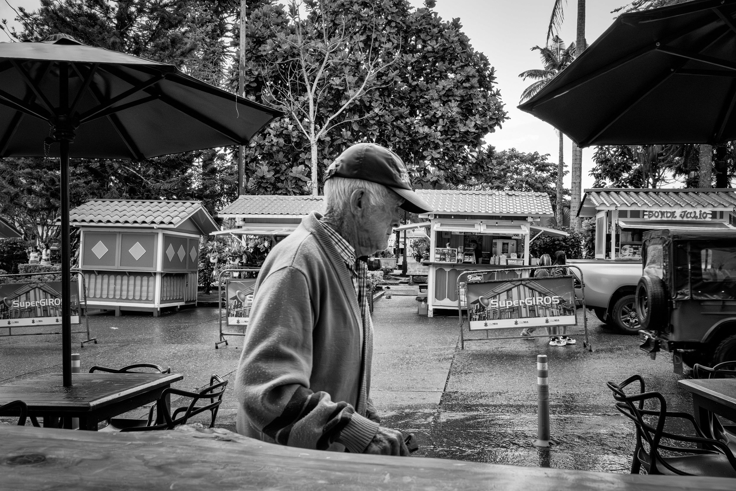 Rainy street scene with people passing by a bar window.