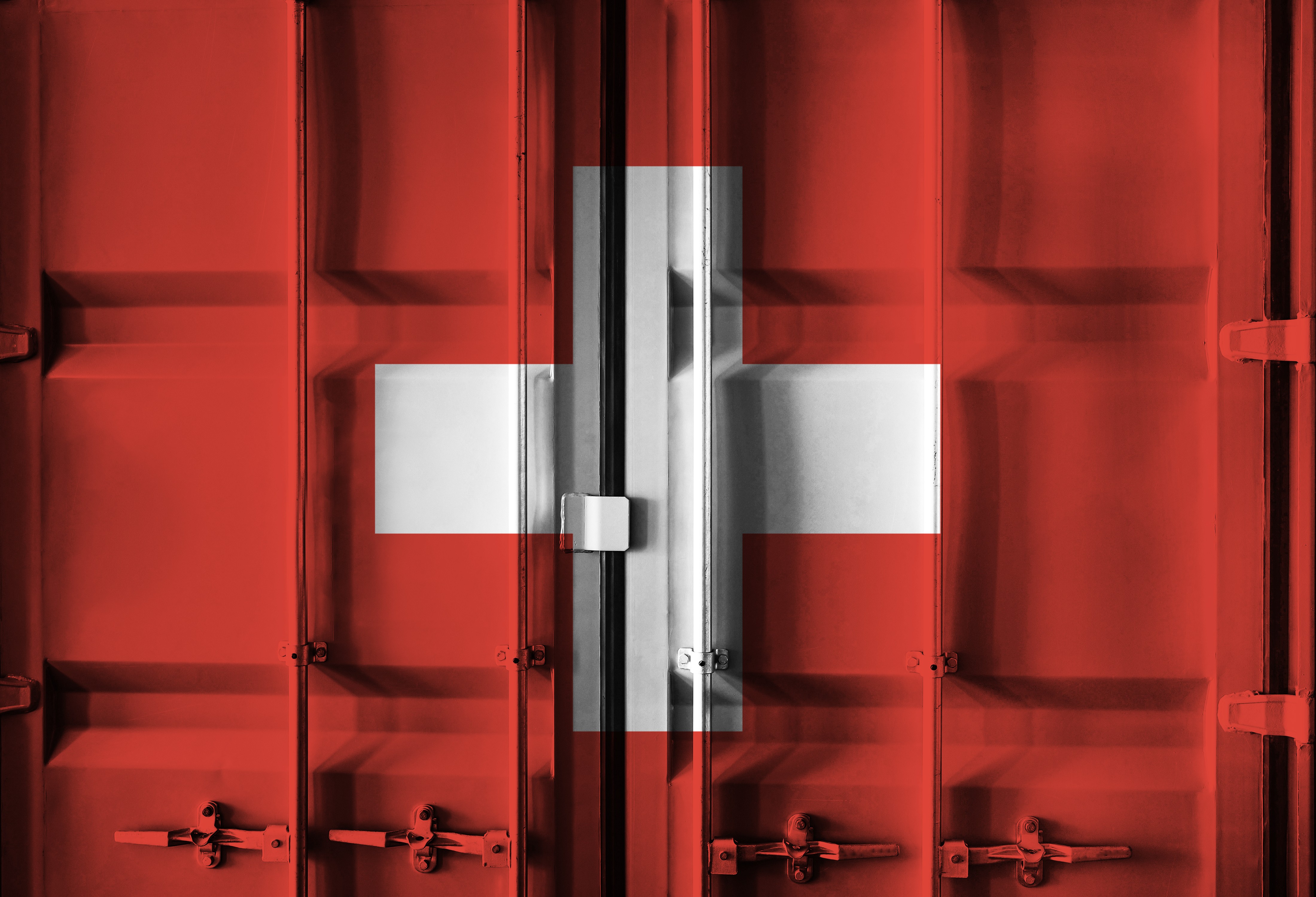A red shipping container with the Swiss Flag painted across the door