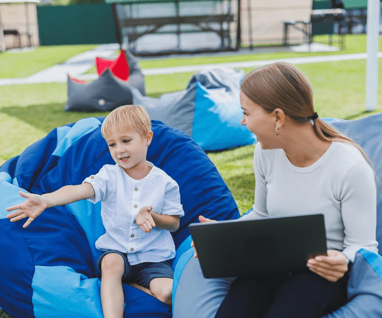 Woman using her laptop with the HoustonPlus app, and looking after the kid.