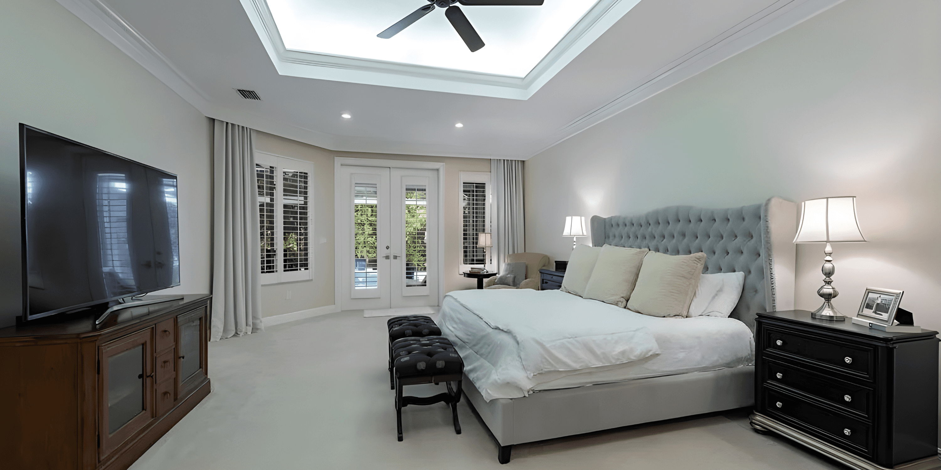 a well lit, modern bedroom with a big white bed and black nightstands