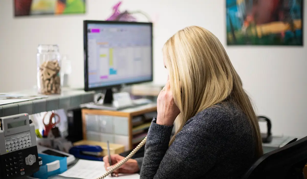 Veterinary CSR on the phone with the PIMS in the background