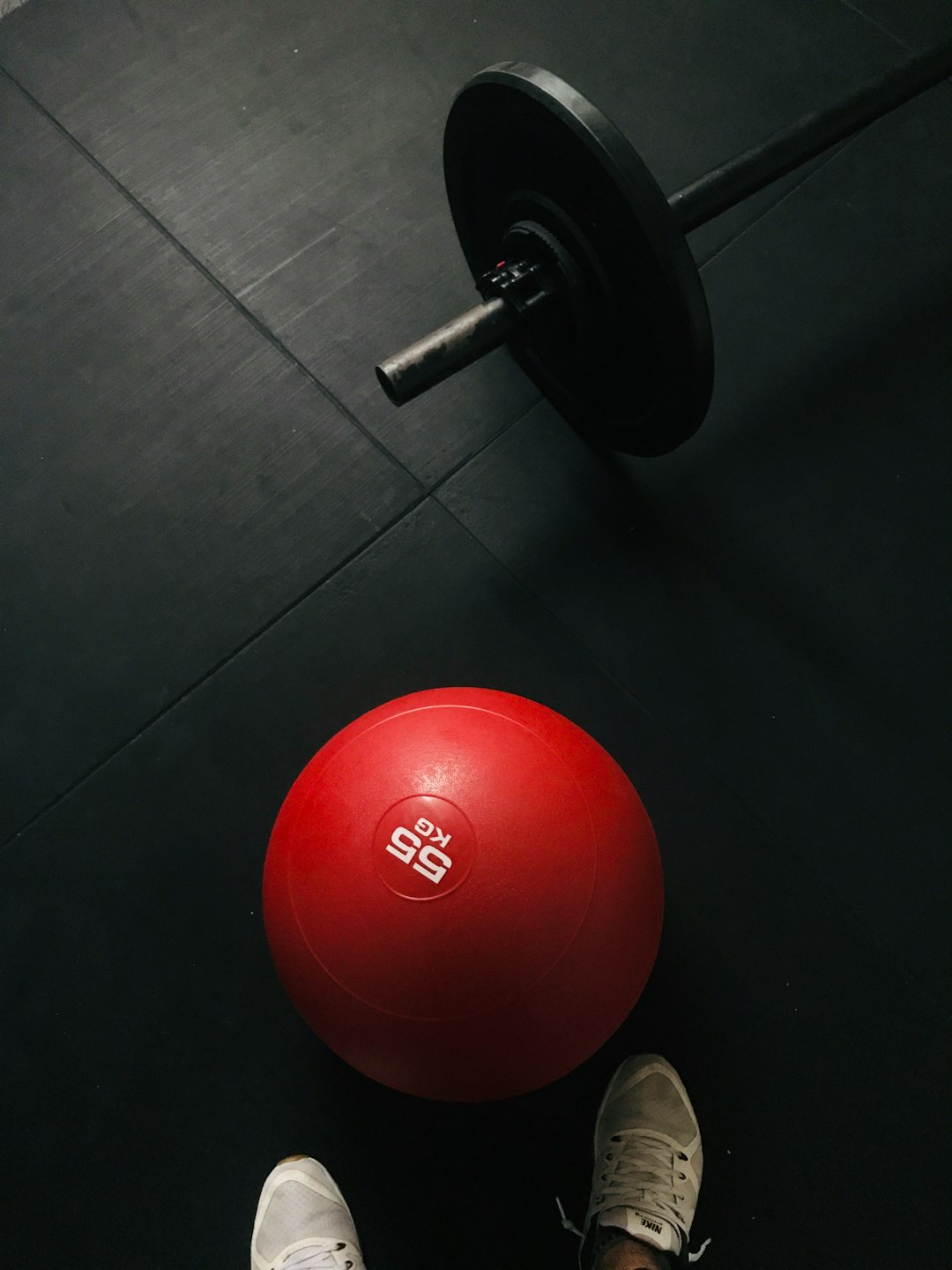 Top-down view of a gym floor with a red medicine ball; the red pops out as the image transitions from grayscale to full color upon being viewed.