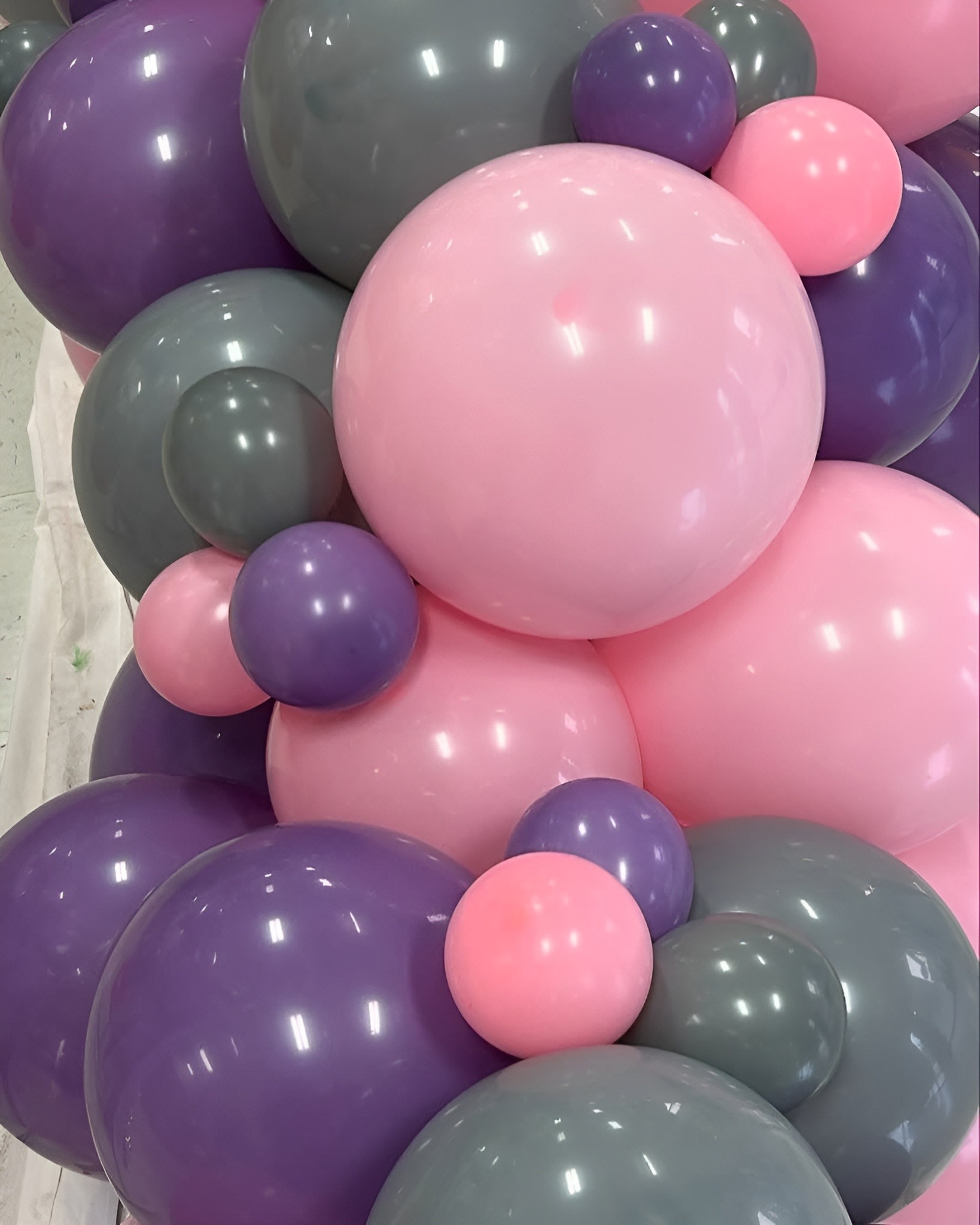Close-up of a balloon cluster featuring pink, purple, and gray balloons arranged for an event by Be Bold Balloons