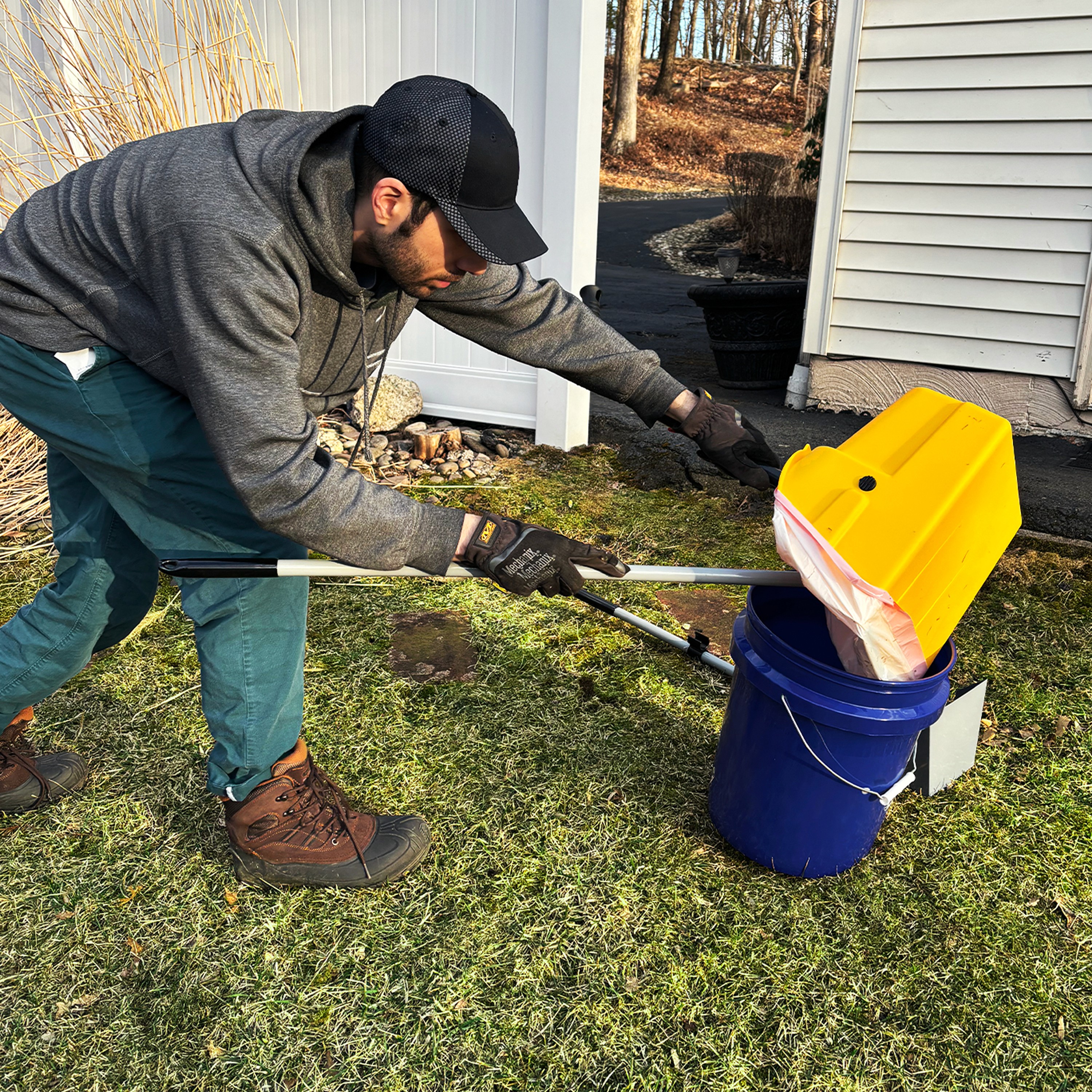 man holding trash bag scooping dog poop