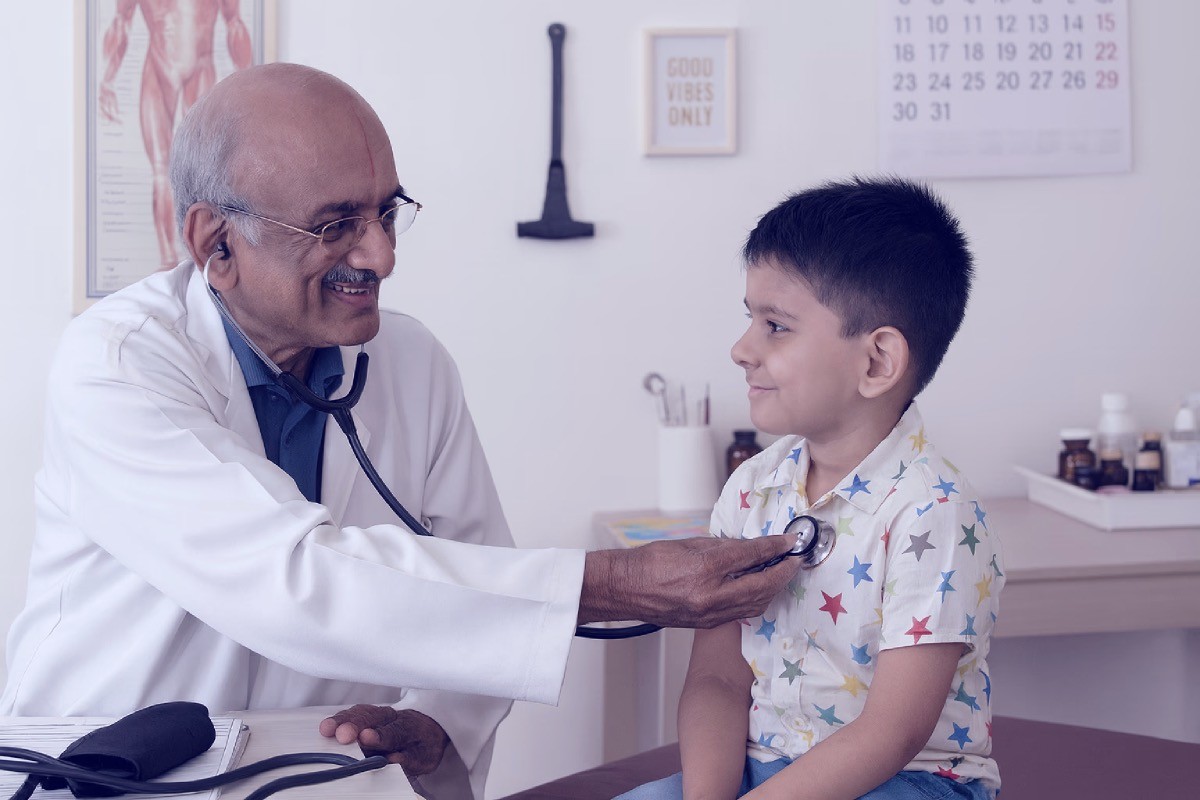 Doctor R Madhavan pediatrician using stethescope to study a young patient with a smile
