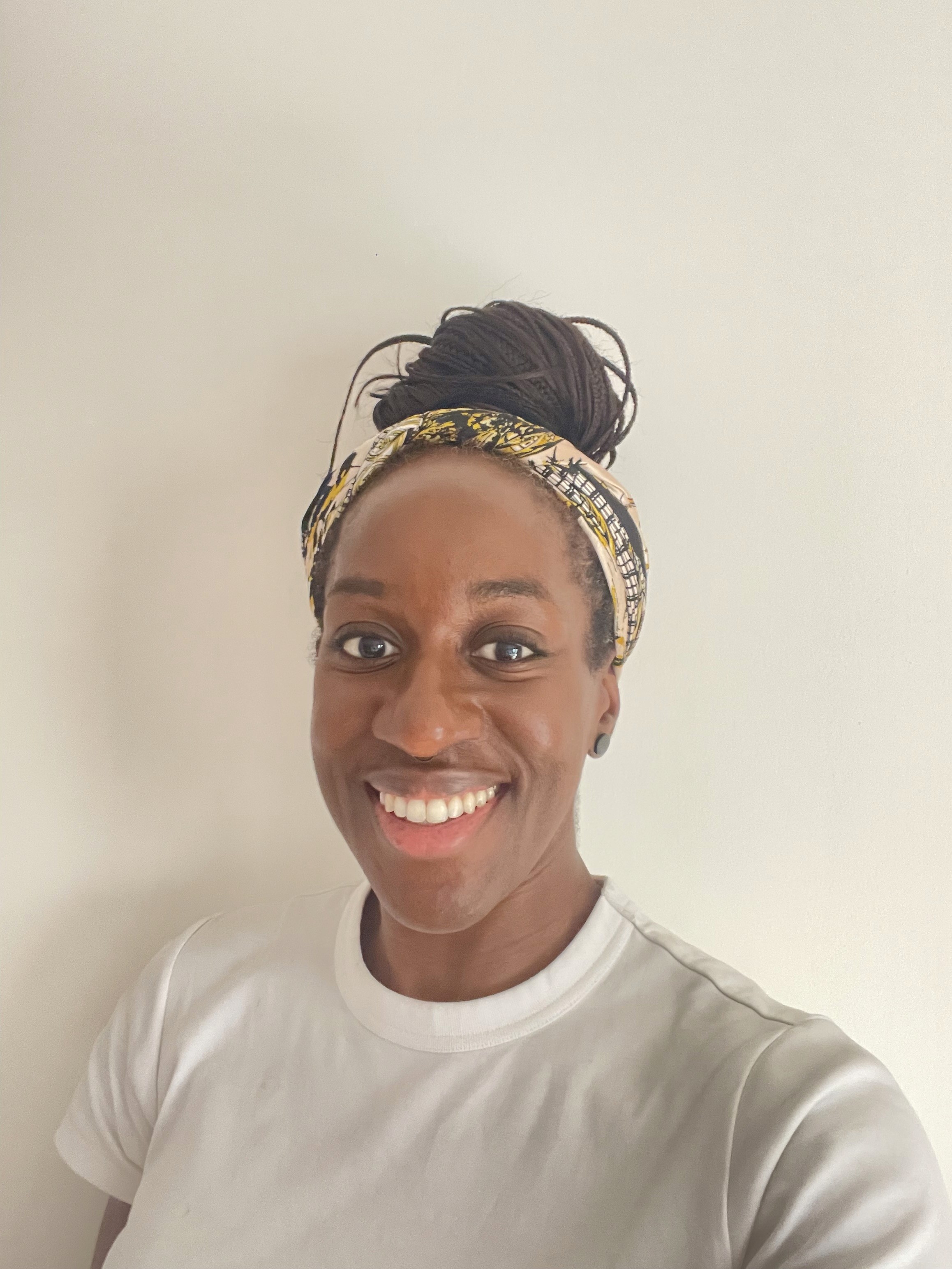 A view from an airplane window shows the aircraft's wing with a golden hue reflecting the setting sun, against a serene backdrop of fluffy clouds and a clear sky.
