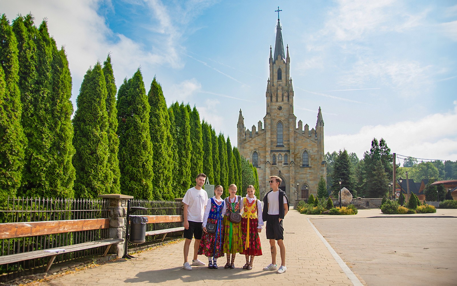 Guests in traditional attire posing near a historic church with tall spires.